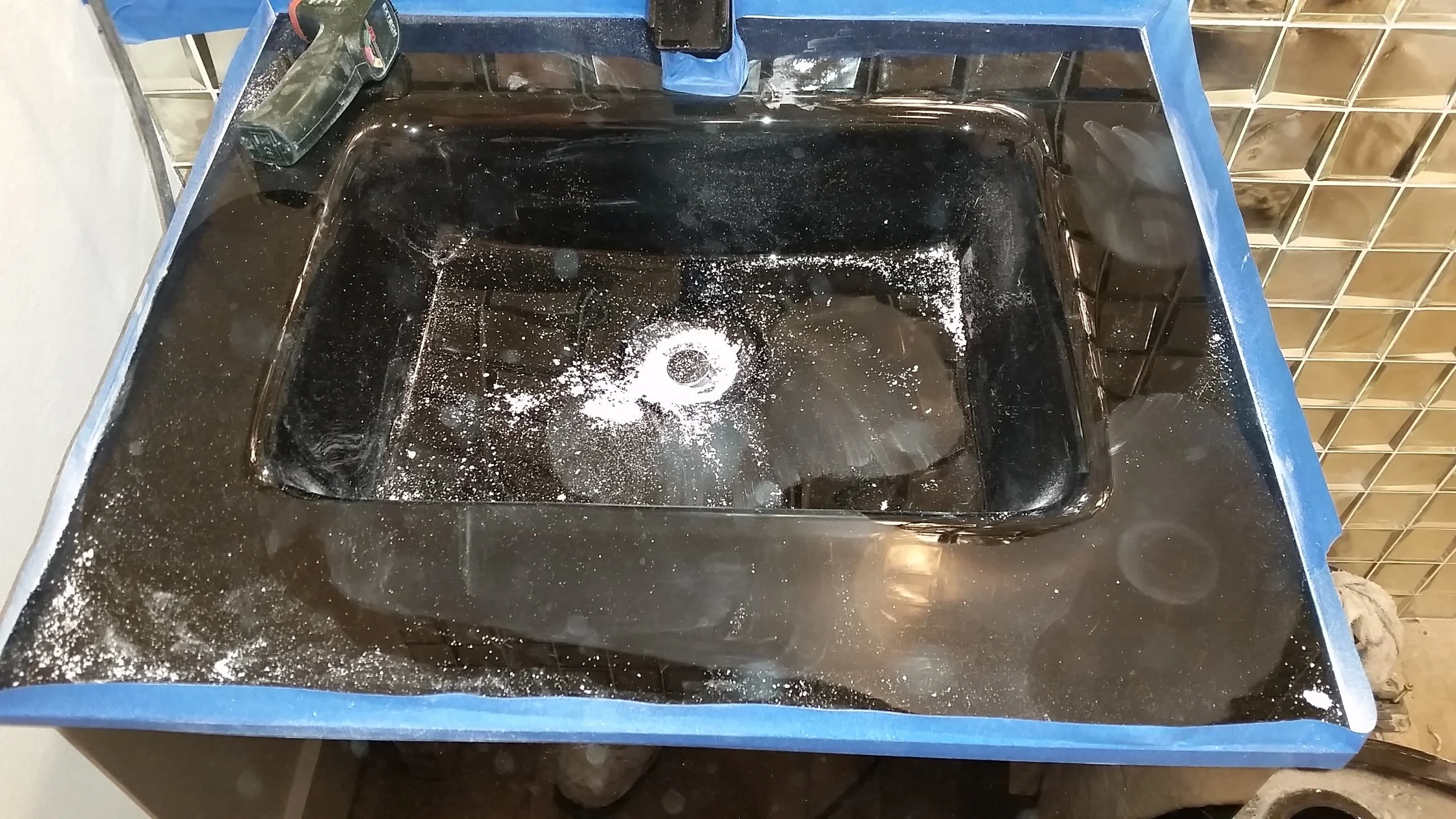Professional scratch removal and restoration of a black glass vessel sink in a Downtown Sarasota luxury condo; restoring deep optical clarity to architectural glass fixtures.