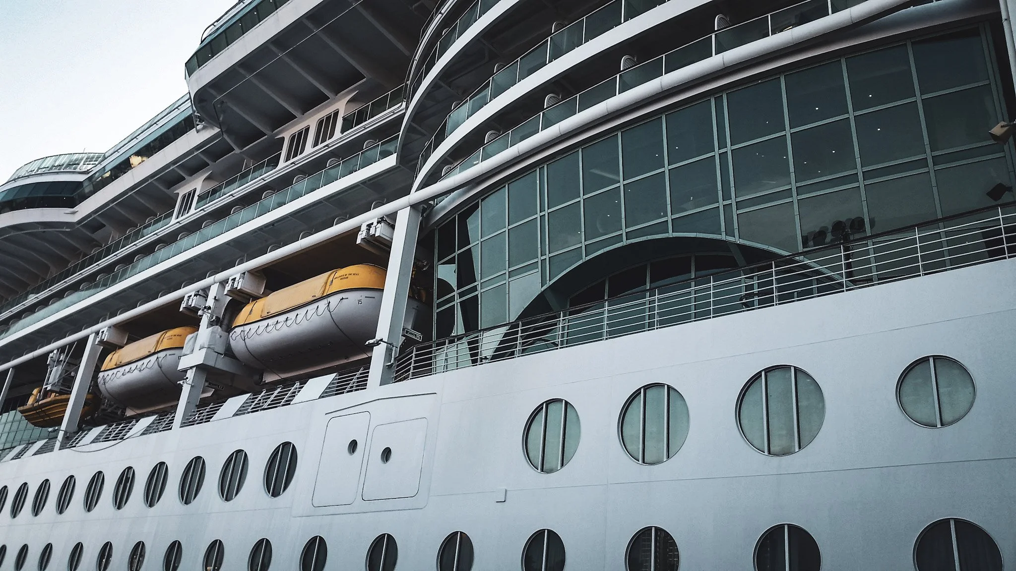 Exterior starboard view of Royal Caribbean's Brilliance of the Seas showing the massive glass facade and porthole berth windows below — docked at Port of Tampa FL, glass consultation by Glass Restoration Inc.