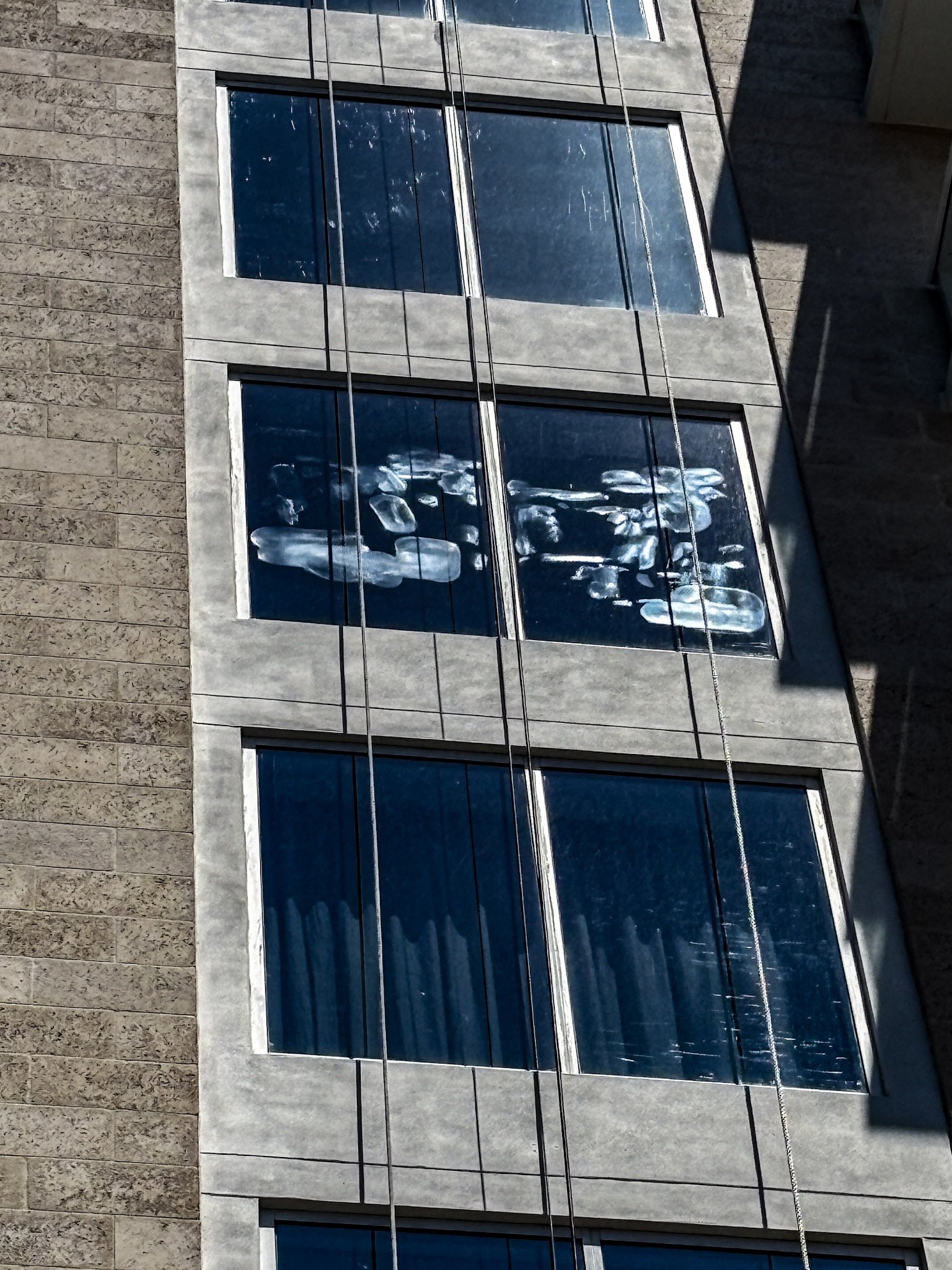 Street-level view of a luxury condominium on Golden Gate Point showing failed glass restoration work with visible haze and optical distortion.
