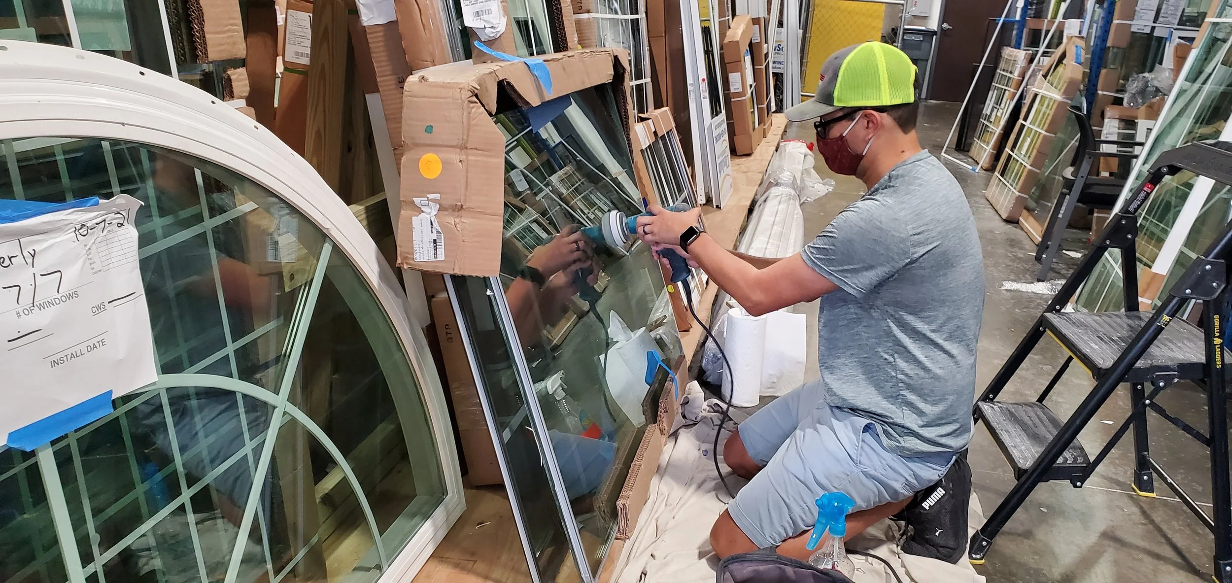 Glass Restoration Inc. technician Skyeler Schmidt polishing scratches from glass in a Tarpon Springs area glass company warehouse — professional on-site glass scratch repair serving Tarpon Springs and northern Pinellas County