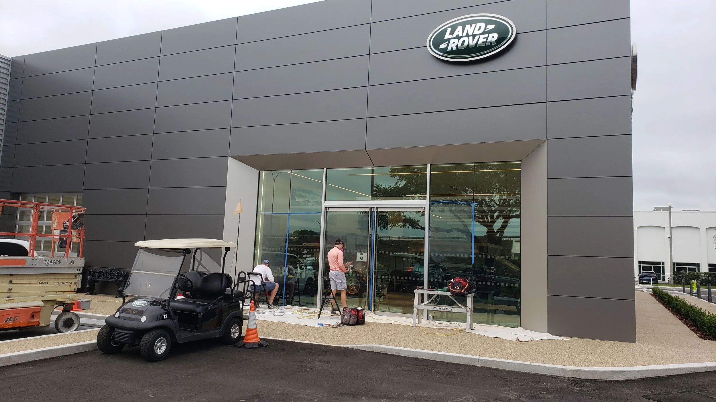 Glass Restoration Inc. technicians Stanton Barbas and Skyeler Schmidt restoring entry storefront glass at a Land Rover dealership in Tampa, FL