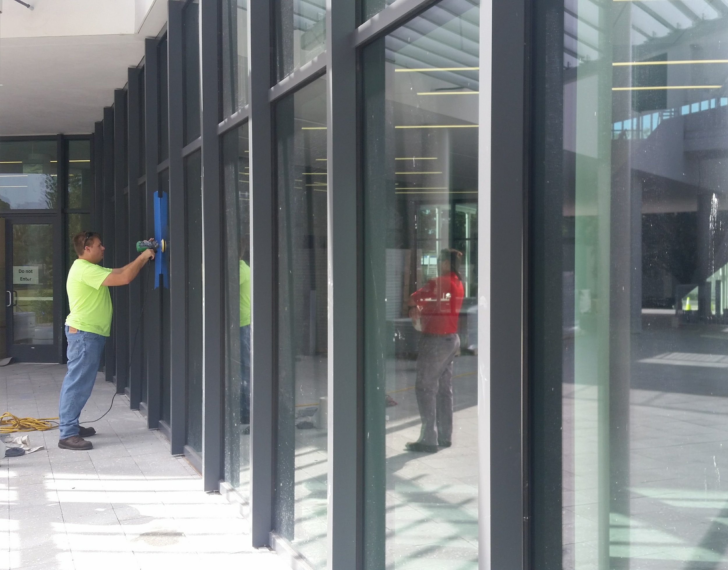 Stanton Barbas performing artisan glass restoration on a large commercial storefront — Glass Restoration Inc. scratch removal specialists serving the Riverview Blvd River District