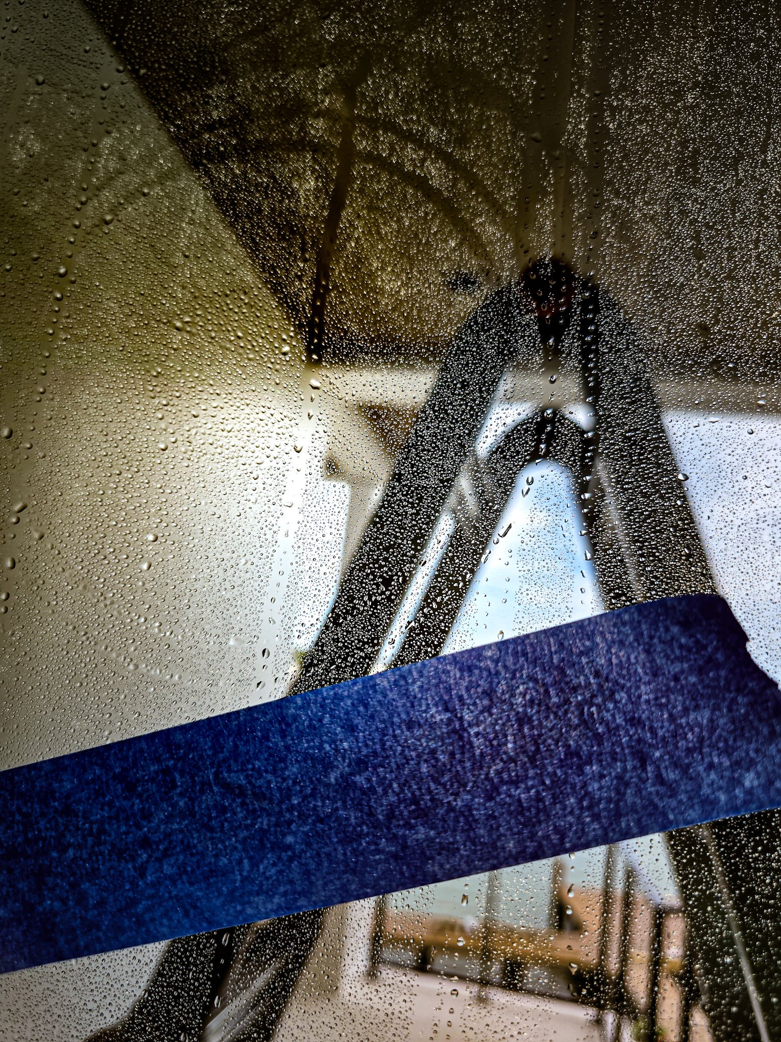 Glass Restoration Inc. technician using misting technique to reveal invisible suction cup silicone marks on glass at a Port Royal Naples FL luxury estate — ladder positioned for high window access