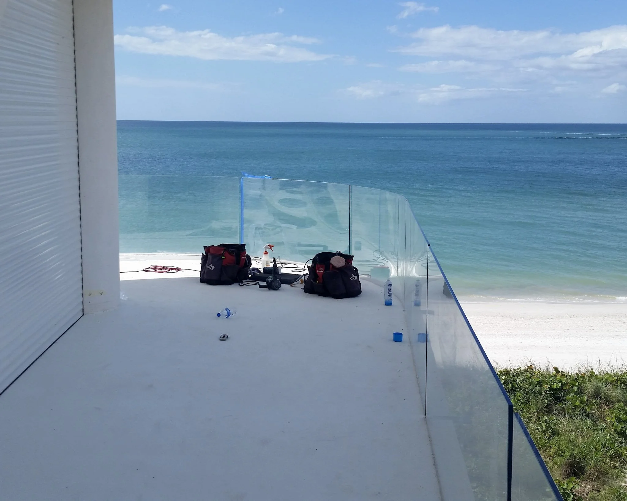 Curved glass balcony railing overlooking the Gulf, restored on-site by Glass Restoration Inc. at a Harbour Island property