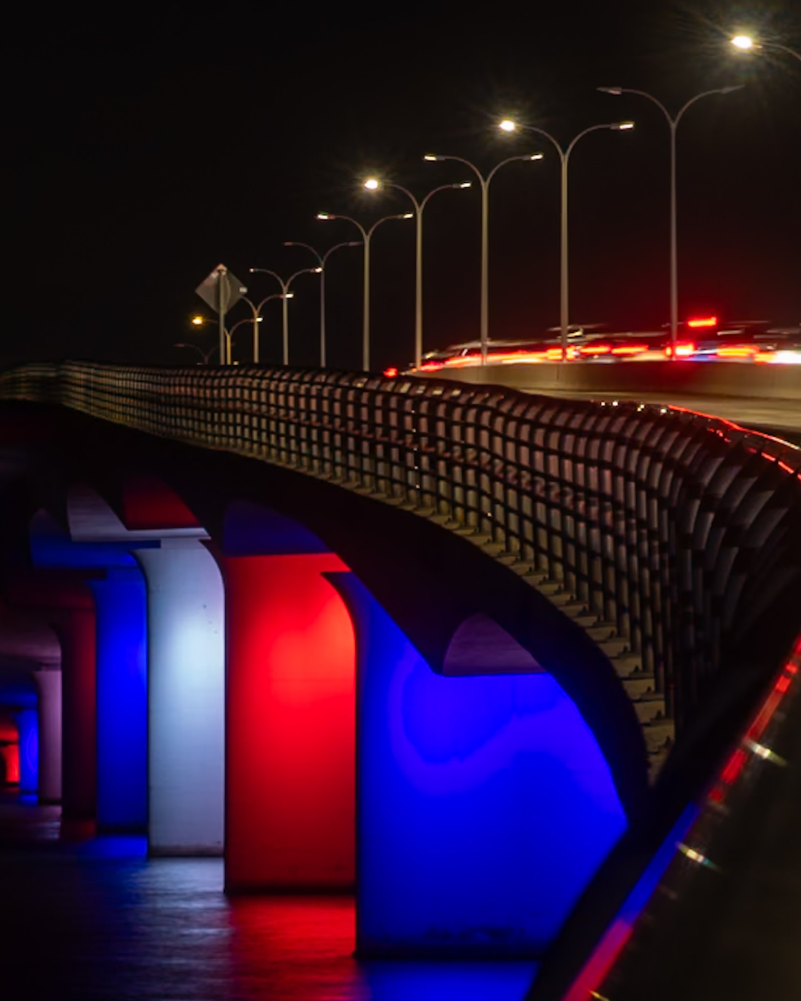 The John Ringling Bridge in Sarasota, FL illuminated red, white, and blue at night — Glass Restoration Inc. proudly serves the Sarasota community