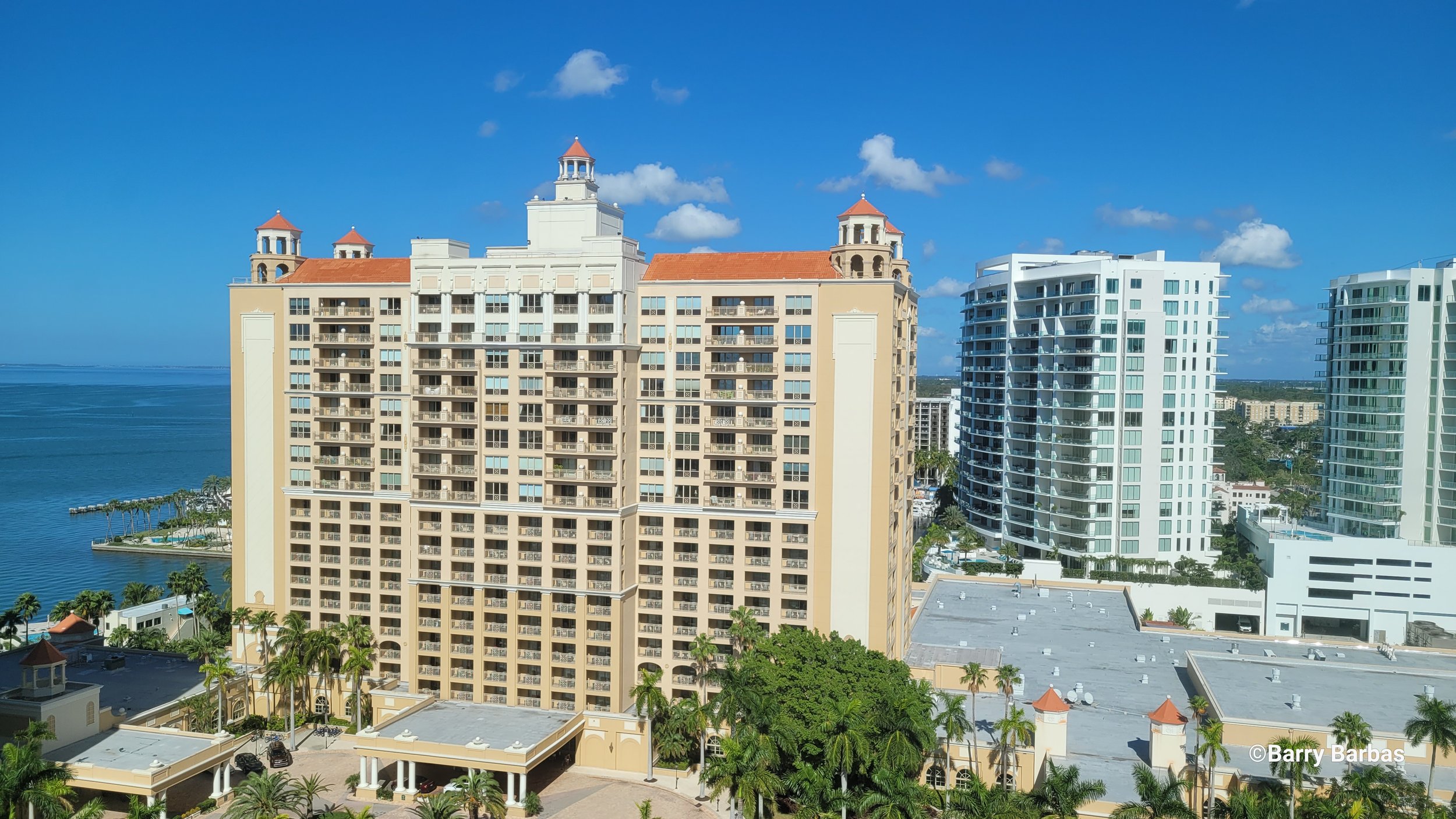 High-rise beachfront buildings with palm trees and ocean view under a clear blue sky.