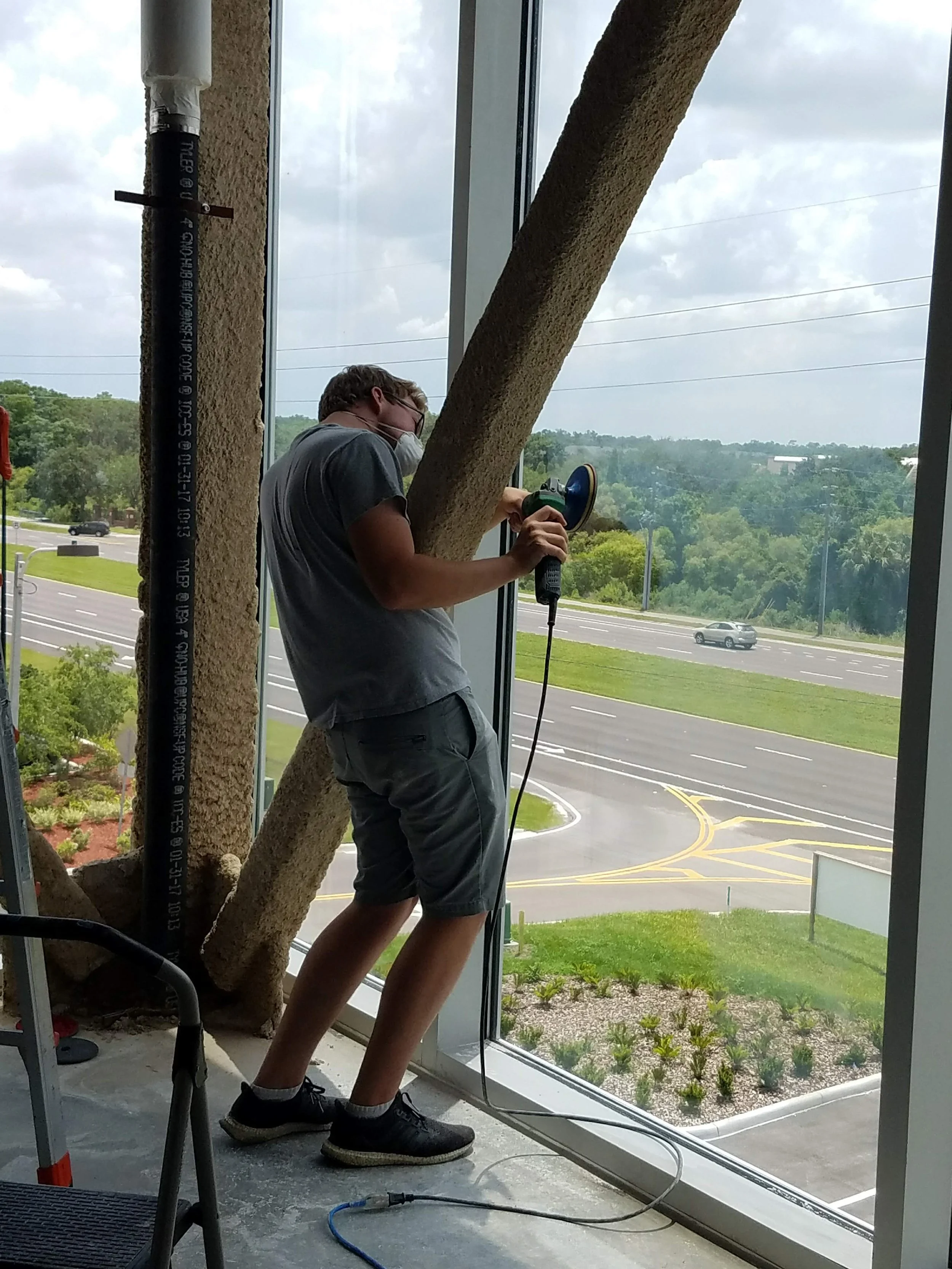 Skyeler Schmidt of Glass Restoration Inc. polishing interior glass at a medical dental building in Lutz Florida — professional commercial glass scratch repair serving Belmont Riverview and south Hillsborough County since 2005