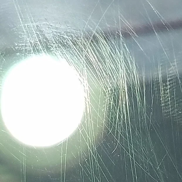 Heavily scratched glass surface in Punta Gorda FL — fine scratch pattern from cleaning tools or wiper blades, restored on site by Glass Restoration Inc. without replacement.