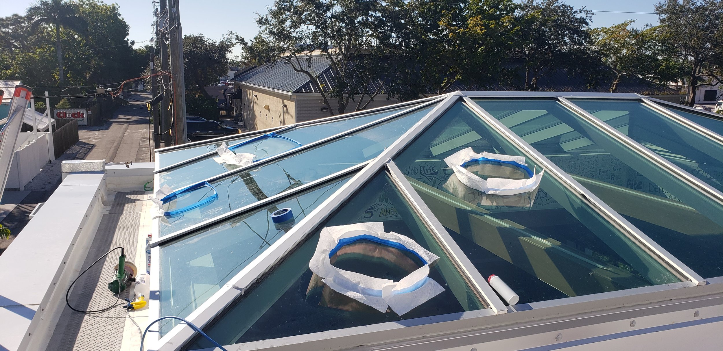 Rooftop view with large glass skylights and tools on a sunny day.