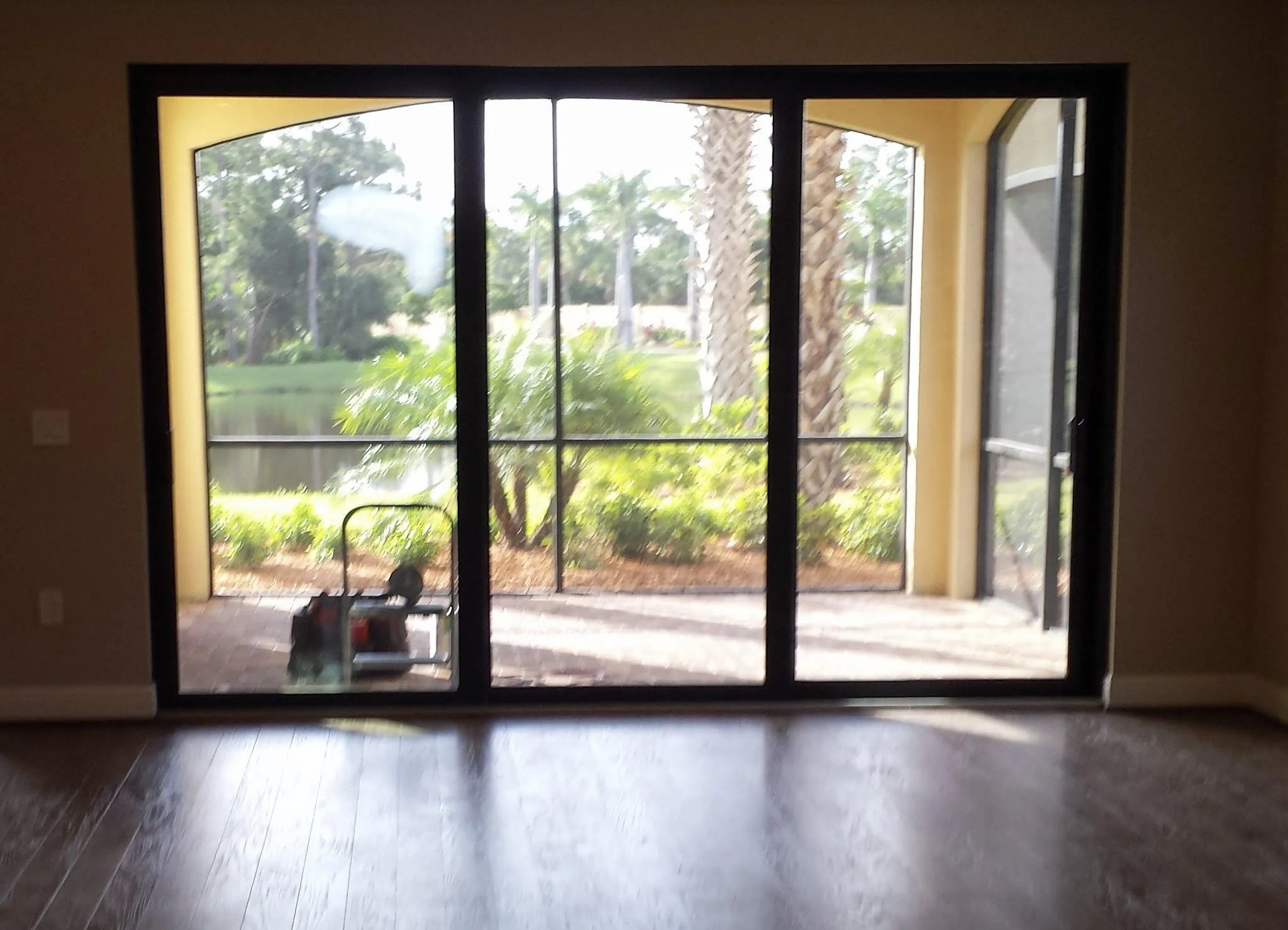 Auburndale Glass Restoration Inc. professional tools and work stool positioned outside a triple sliding glass door ready for on-site glass scratch repair — serving Auburndale FL and new construction builders throughout Polk County