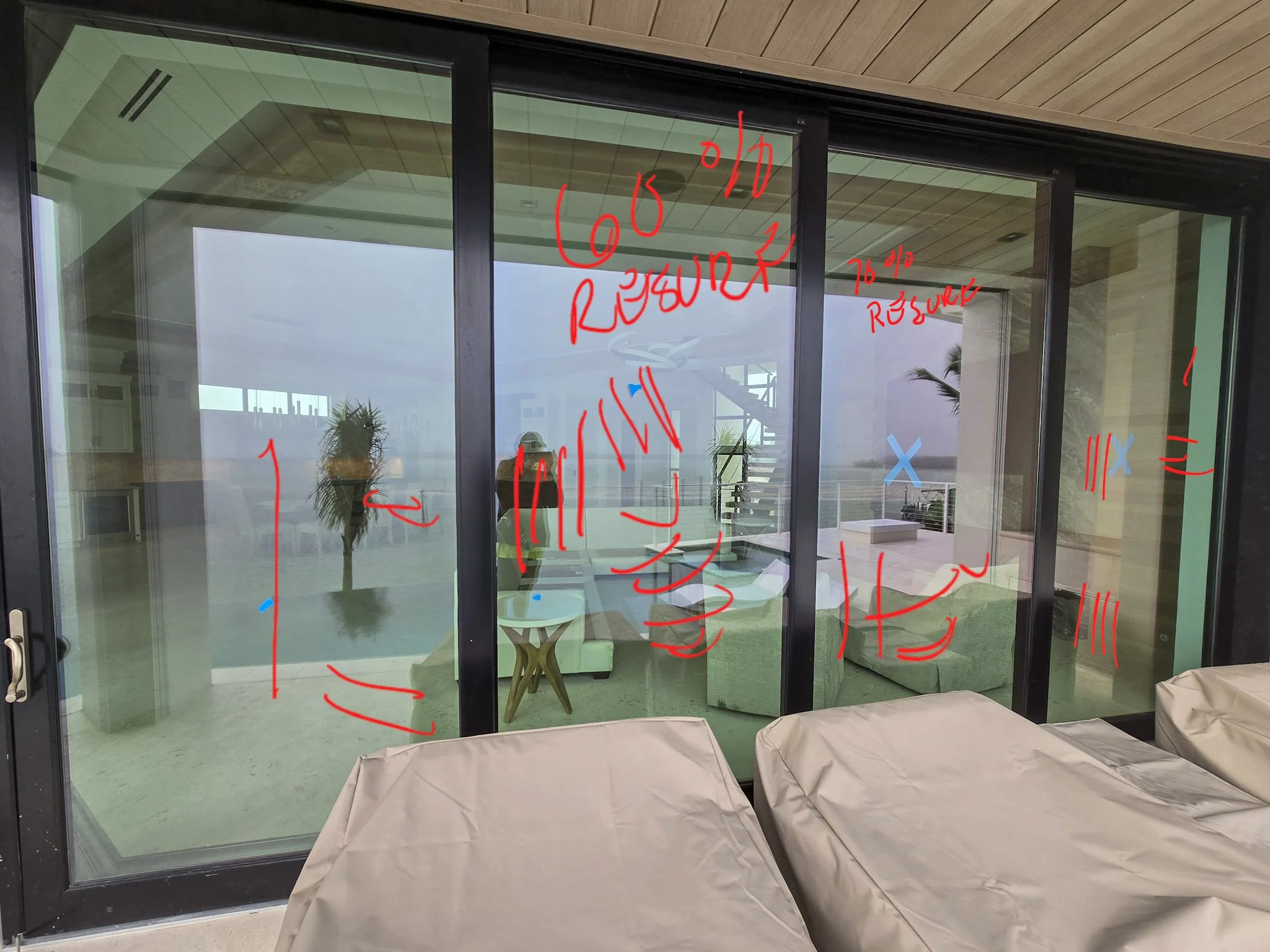 A four-panel sliding glass door set on a custom waterfront home featuring pre-restoration markups of construction-related scratches and surface damage prior to precision resurfacing by Glass Restoration Inc.