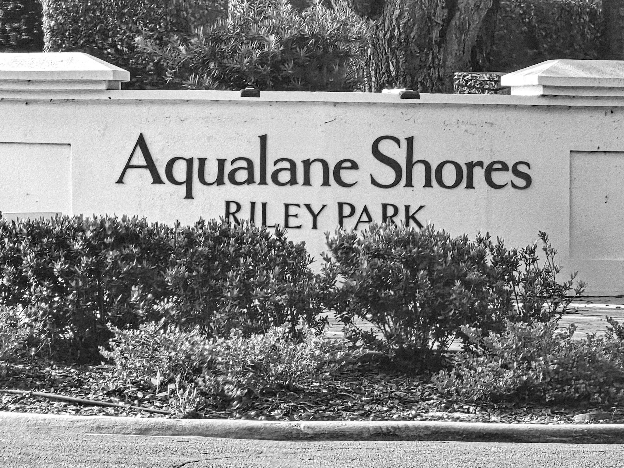 Aqualane Shores Riley Park neighborhood entrance monument sign in Naples FL — monochrome — a luxury waterfront community adjacent to Port Royal served by Glass Restoration Inc.