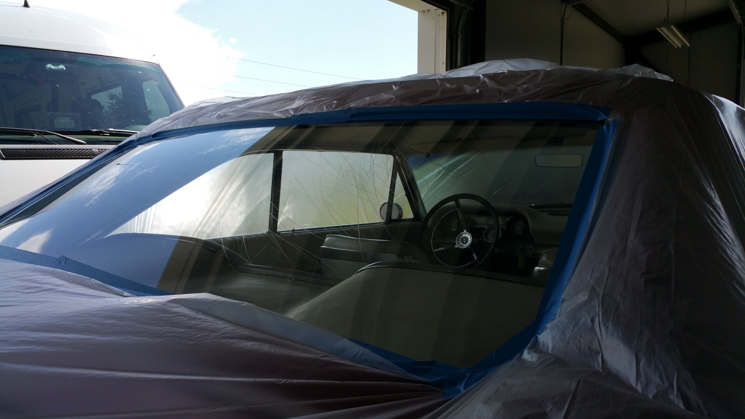 Car with windshield covered, possibly for repair for scratches in glass rear window