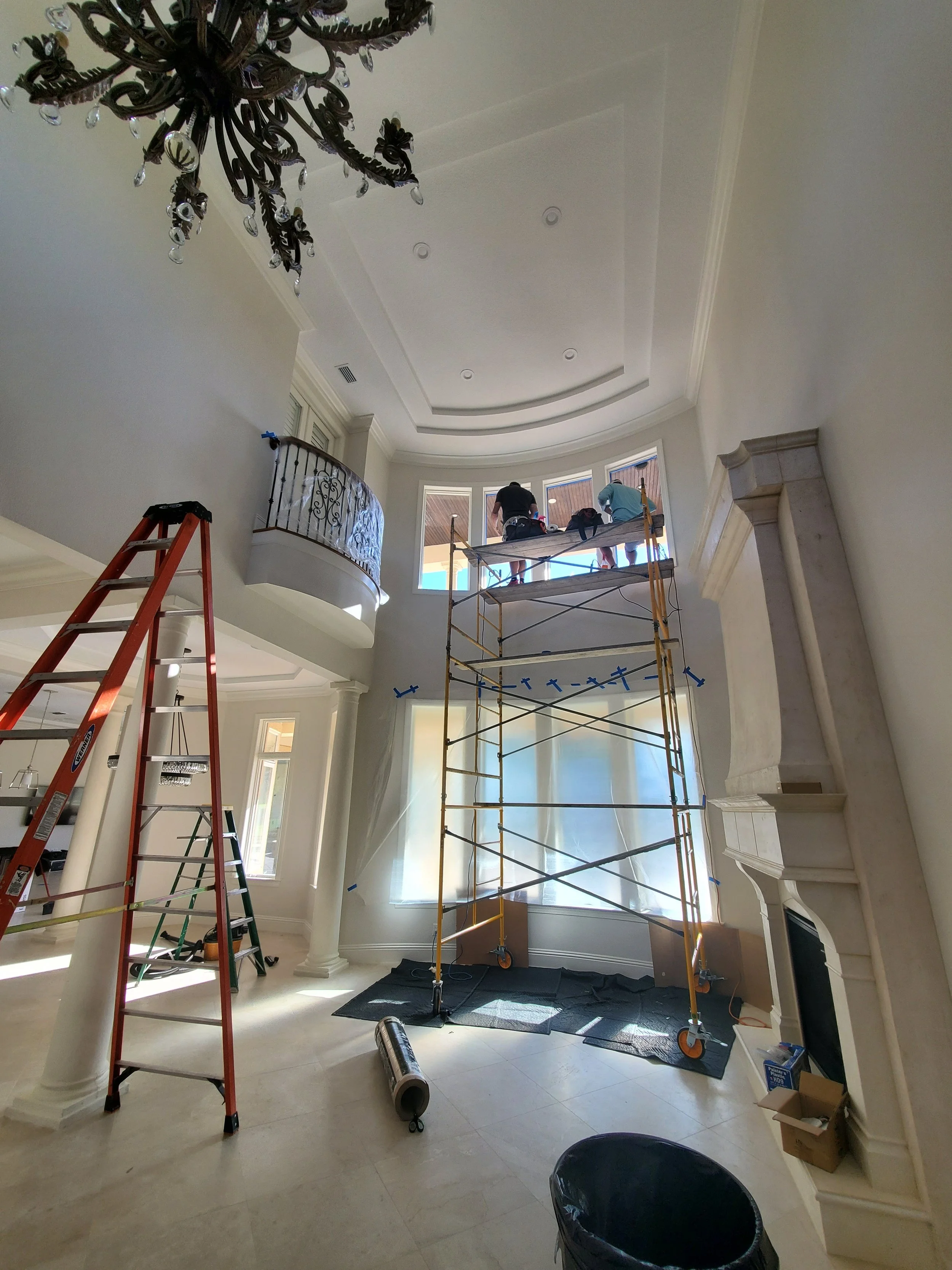 Glass Restoration Inc. crew working on scaffold restoring interior windows 18 feet above floor level in a large custom home — no access challenge is too difficult for our team serving south Hillsborough County and the Florida Gulf Coast