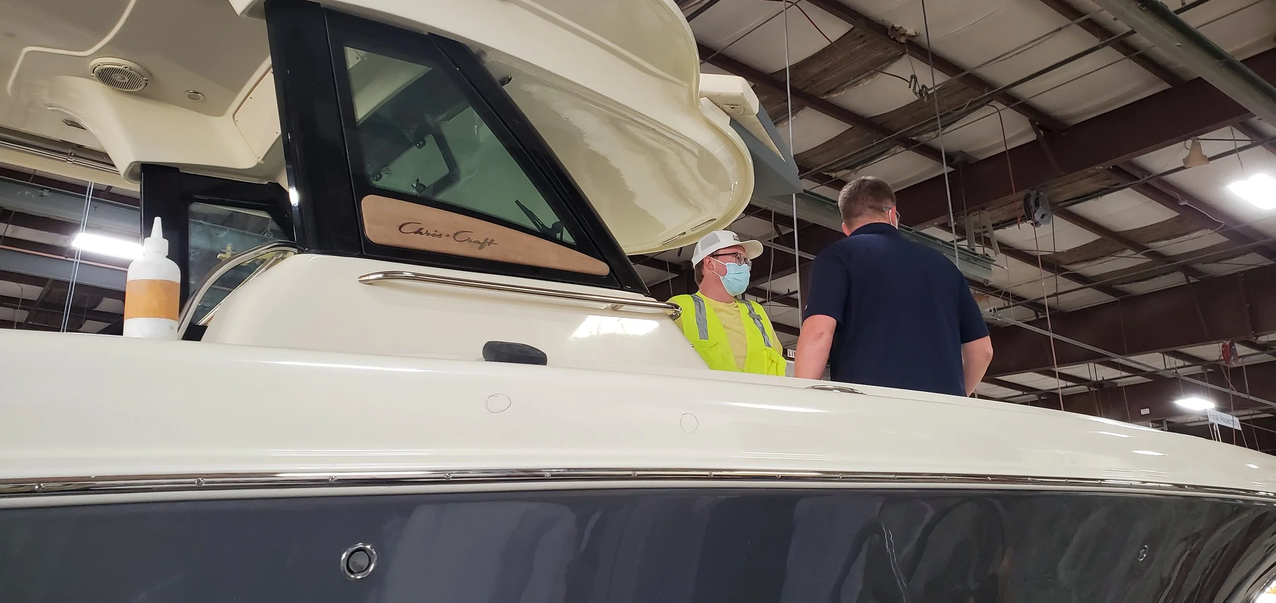 Glass Restoration Inc. technicians Stanton Barbas and Skyeler Schmidt performing glass restoration at the Chris-Craft yacht factory — verified marine glass restoration specialists serving The Inlets Bradenton FL and Sarasota Bay boating community