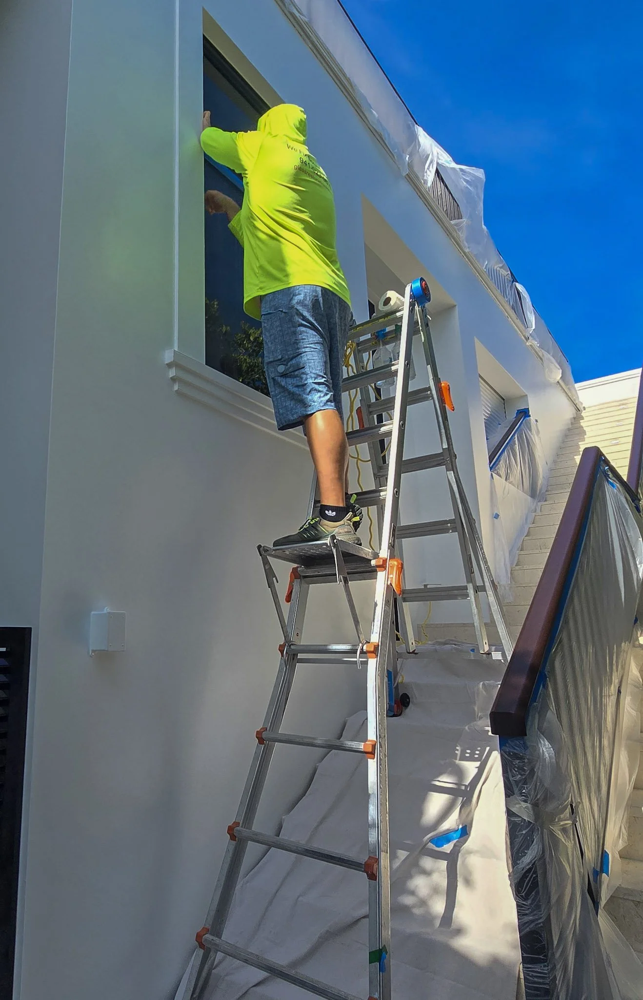 Glass Restoration Inc. lead technician Stanton Barbas polishing scratches from a window on a ladder at a $5 million home in Tarpon Springs Florida