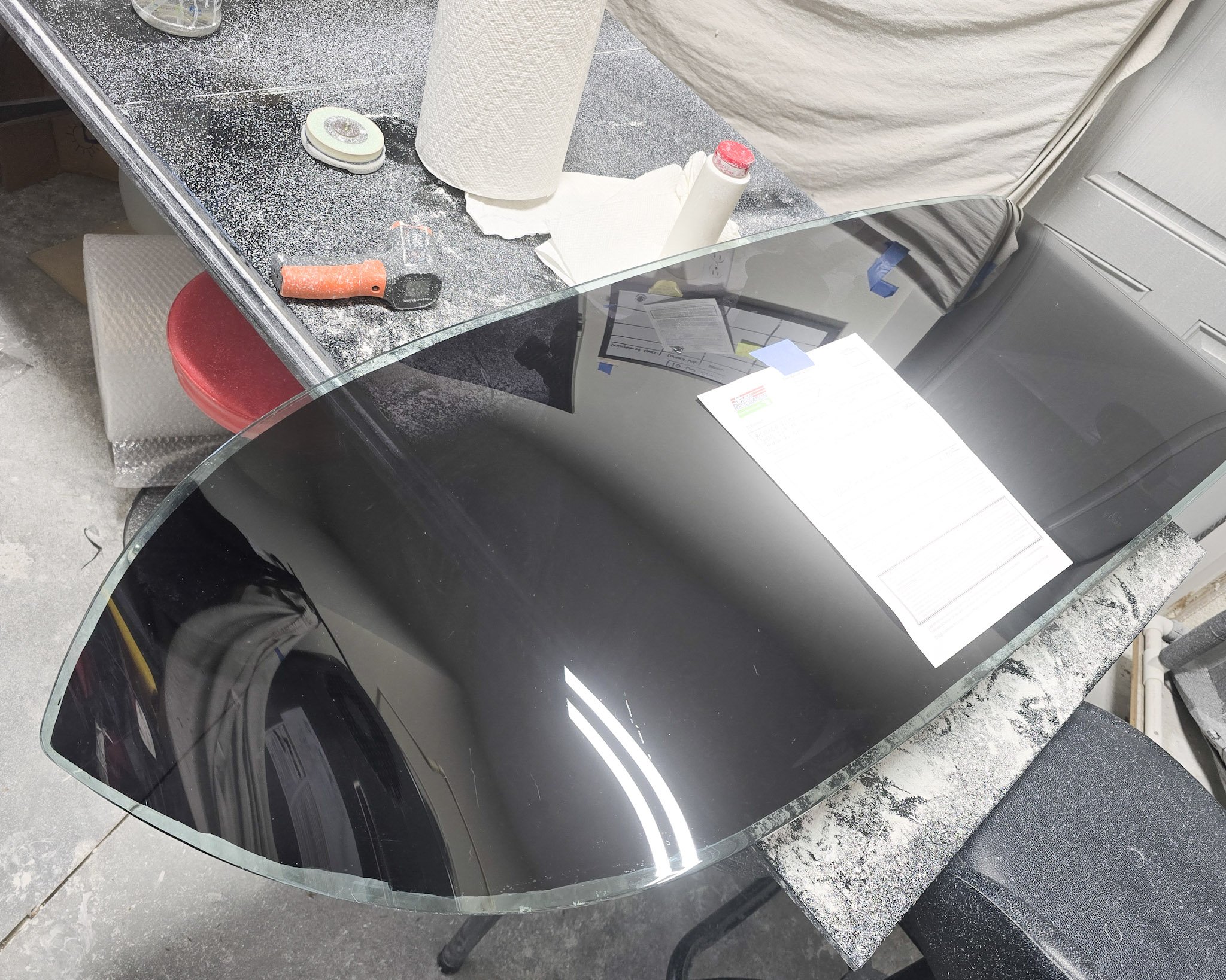 Large curved glass panel on a worktable at Glass Restoration Inc. — radius bent glass scratch repair and restoration, Florida.