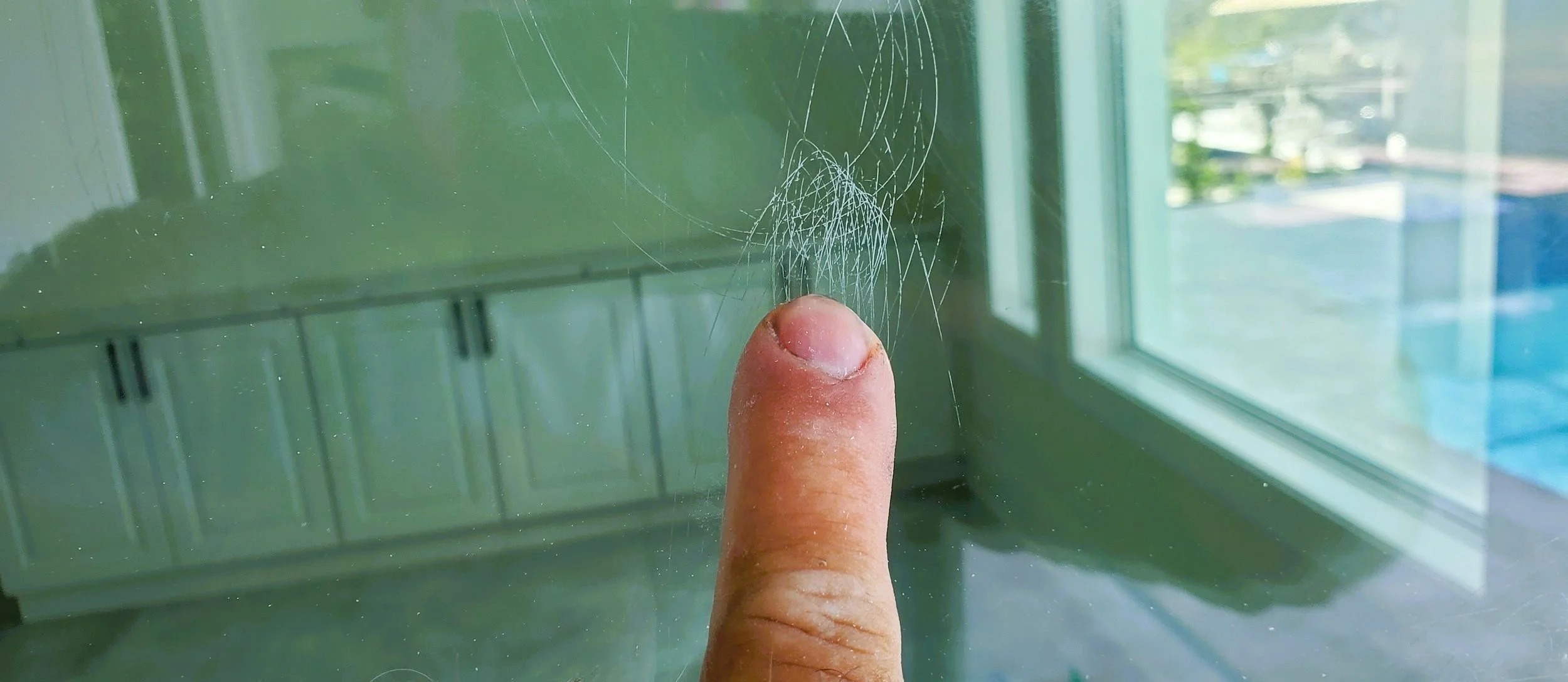 Close-up of deep scratches on a glass surface before restoration, demonstrating the type of severe damage Glass Restoration Inc. can repair without replacement.