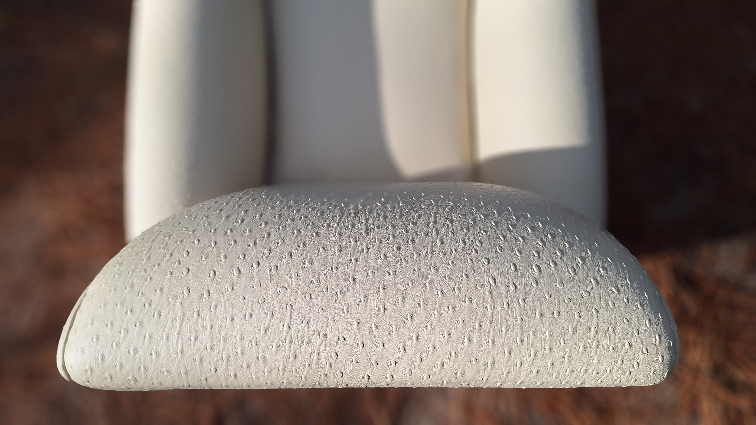 Fauteuil club art nouveau déytail du dossier en photo dans la foret des landes. Réalisé en cuir végétal, impression autruche couleur mascarpone, issus du recyclage de déchets de l'industrie forestière (sciure de bois), visible à Sanguinet, Nord des L