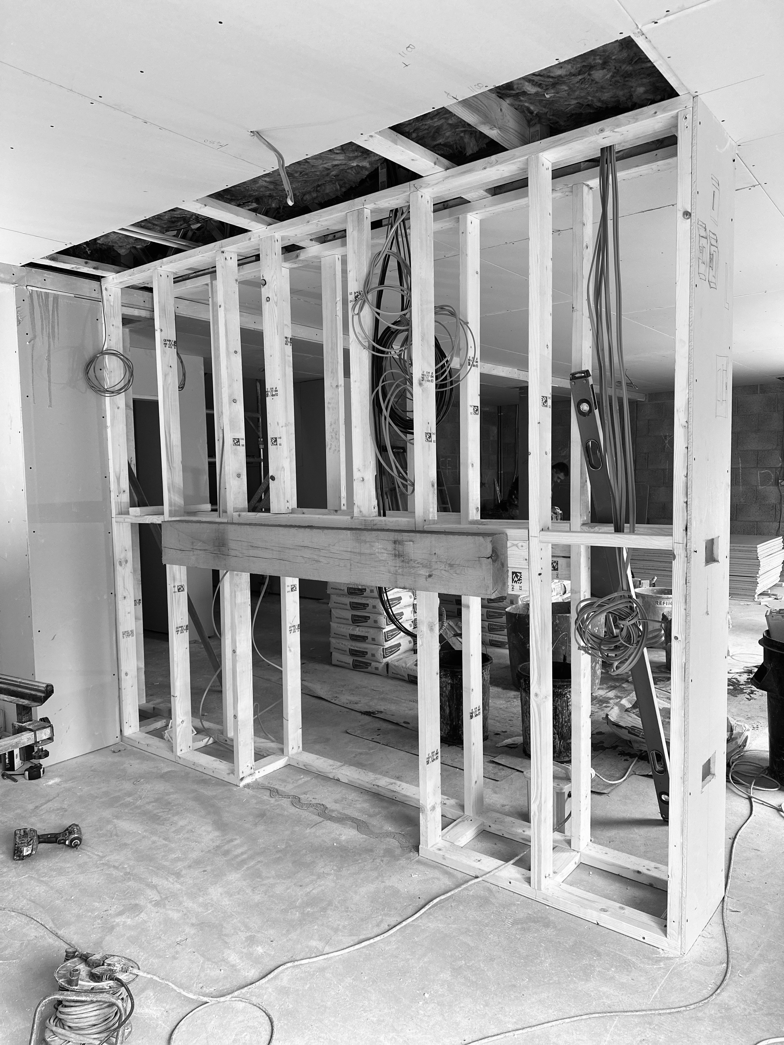 Wooden framing structure in a room under construction with exposed wiring and tools.