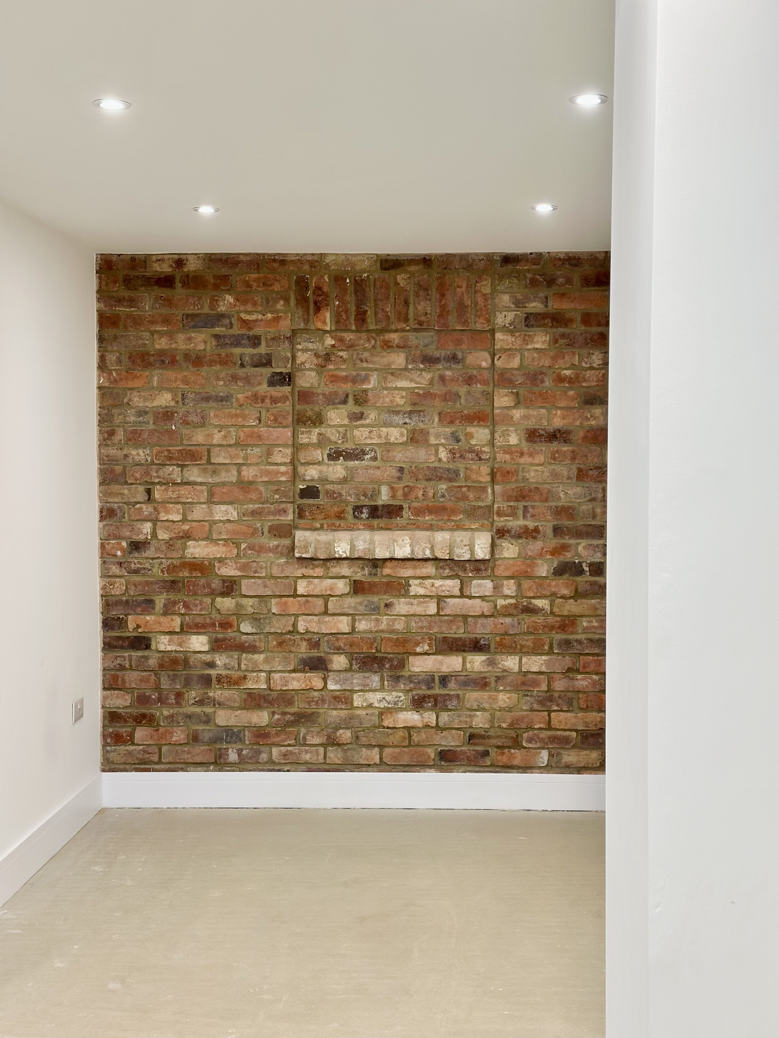 Small room with brick wall, recessed lighting, and white walls