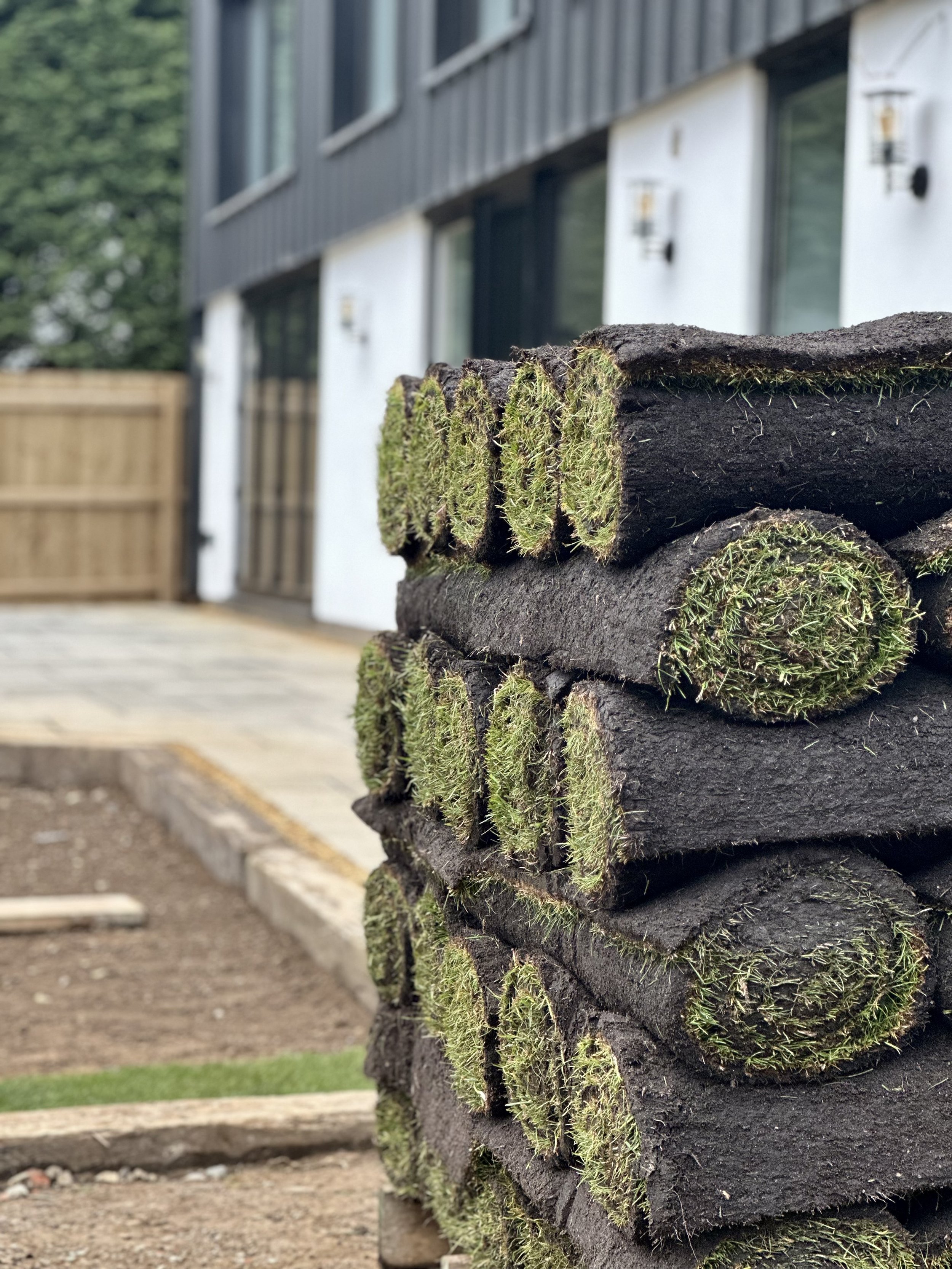 Stack of rolled grass sod in front of a modern building