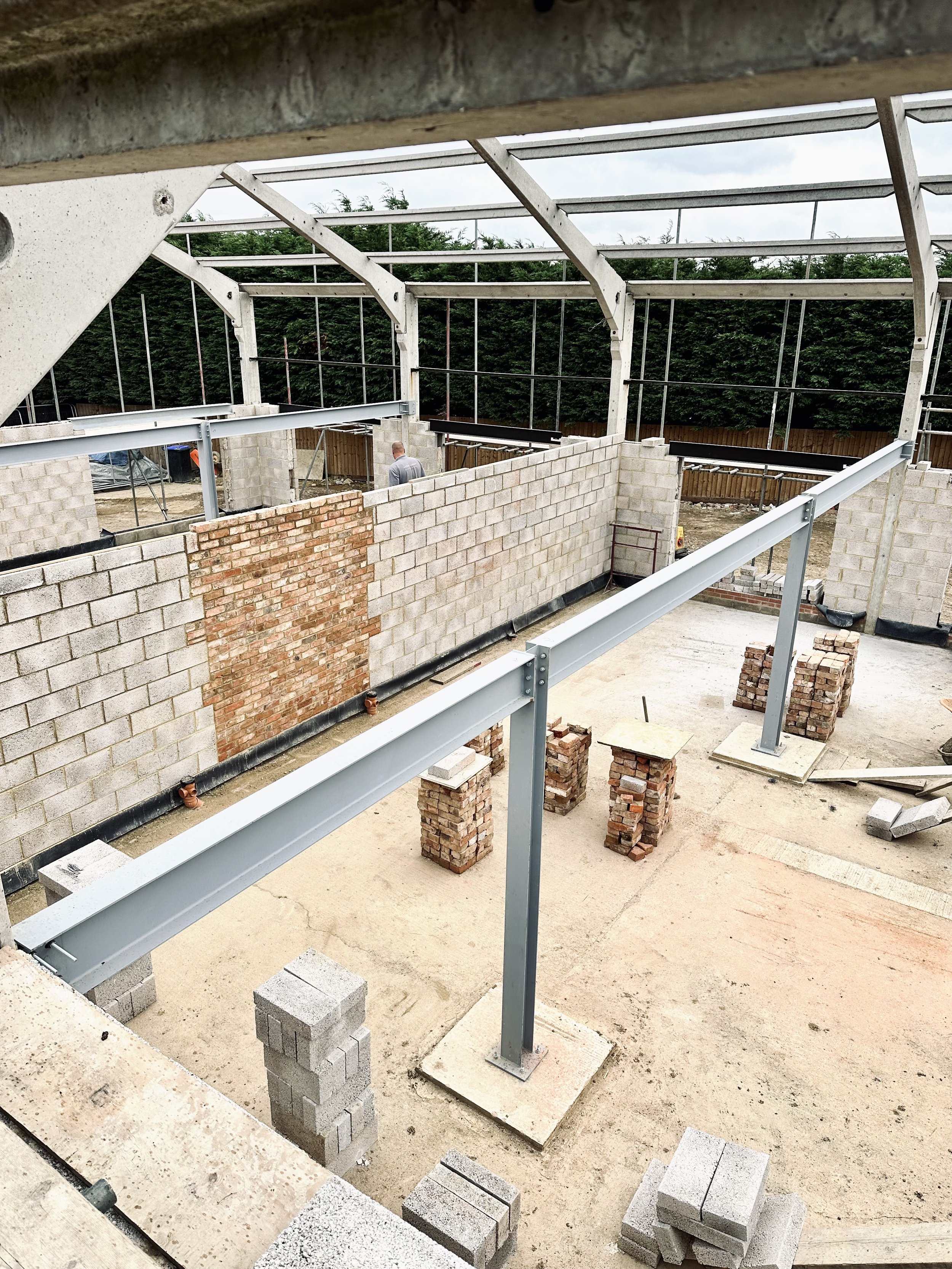 Construction site of a building with concrete blocks, steel beams, and unfinished brick walls.