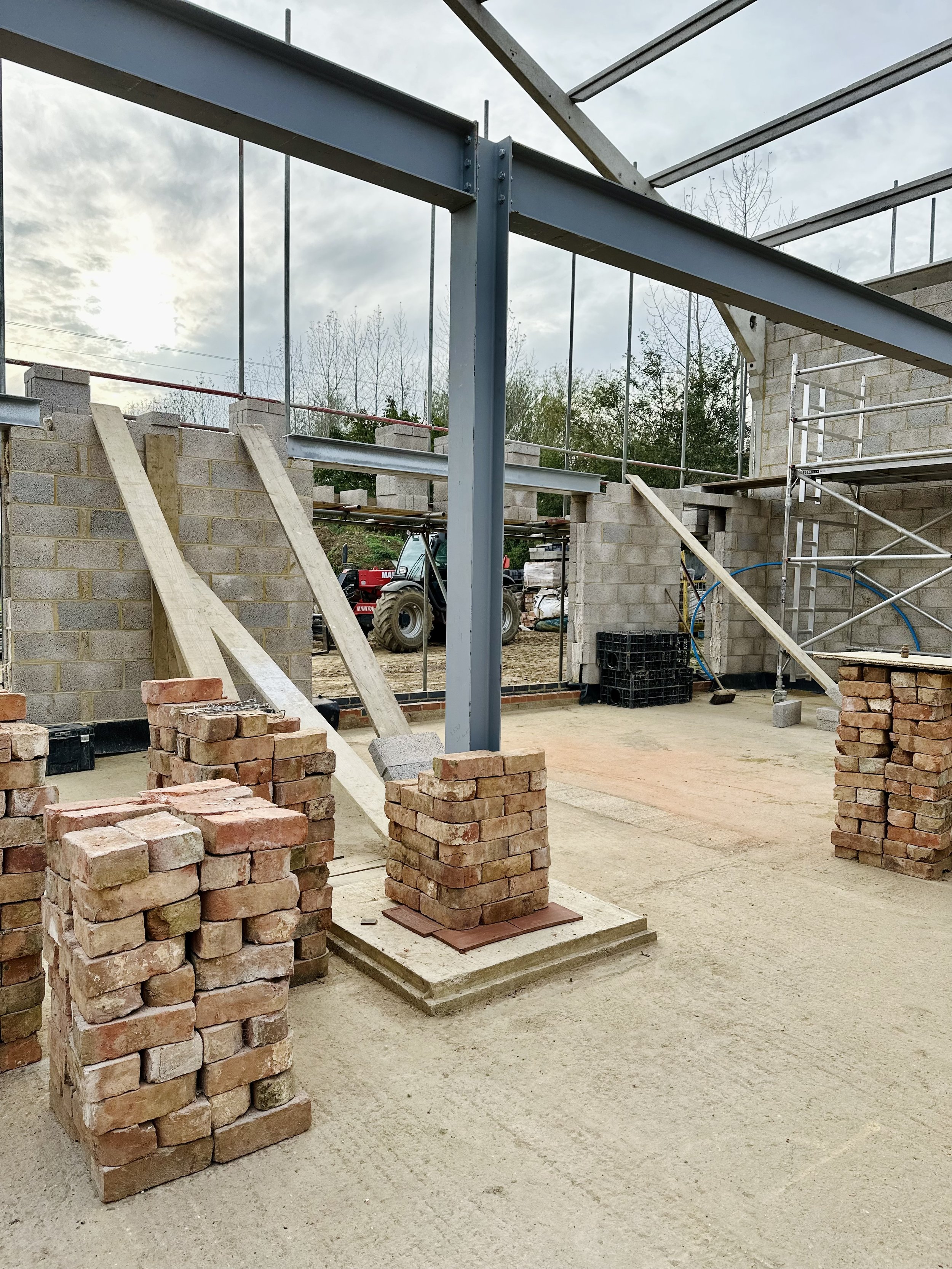 Construction site with steel framework, brick stacks, and scaffolding
