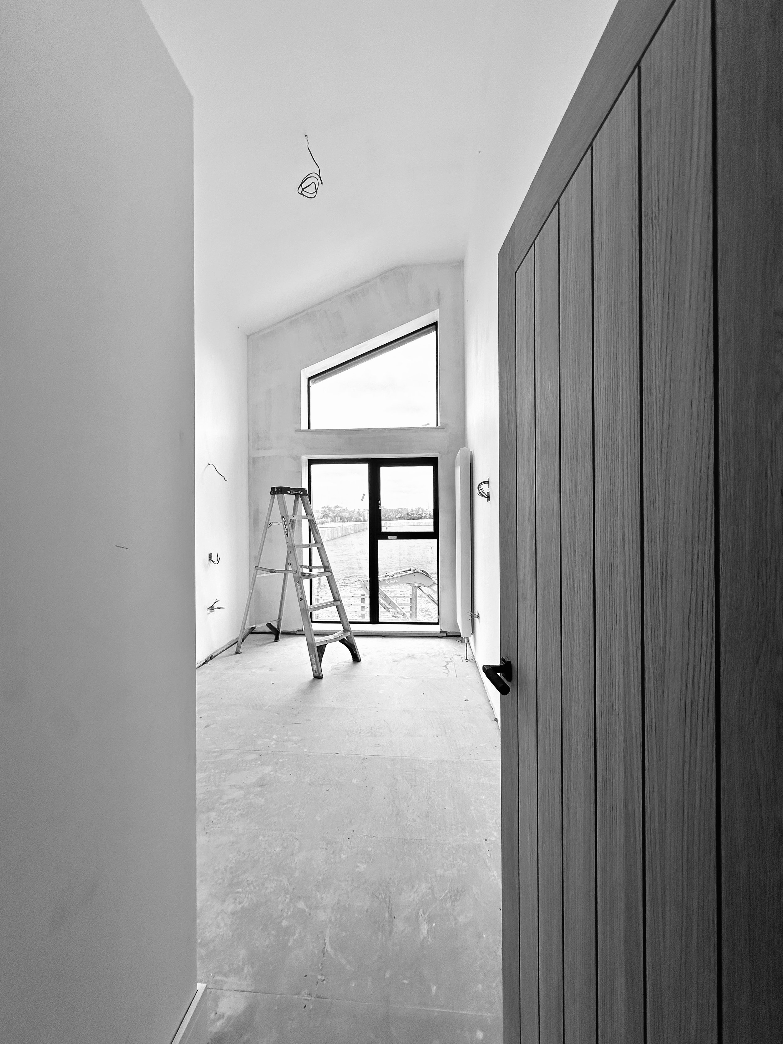 Interior of unfinished room with tall window and ladder