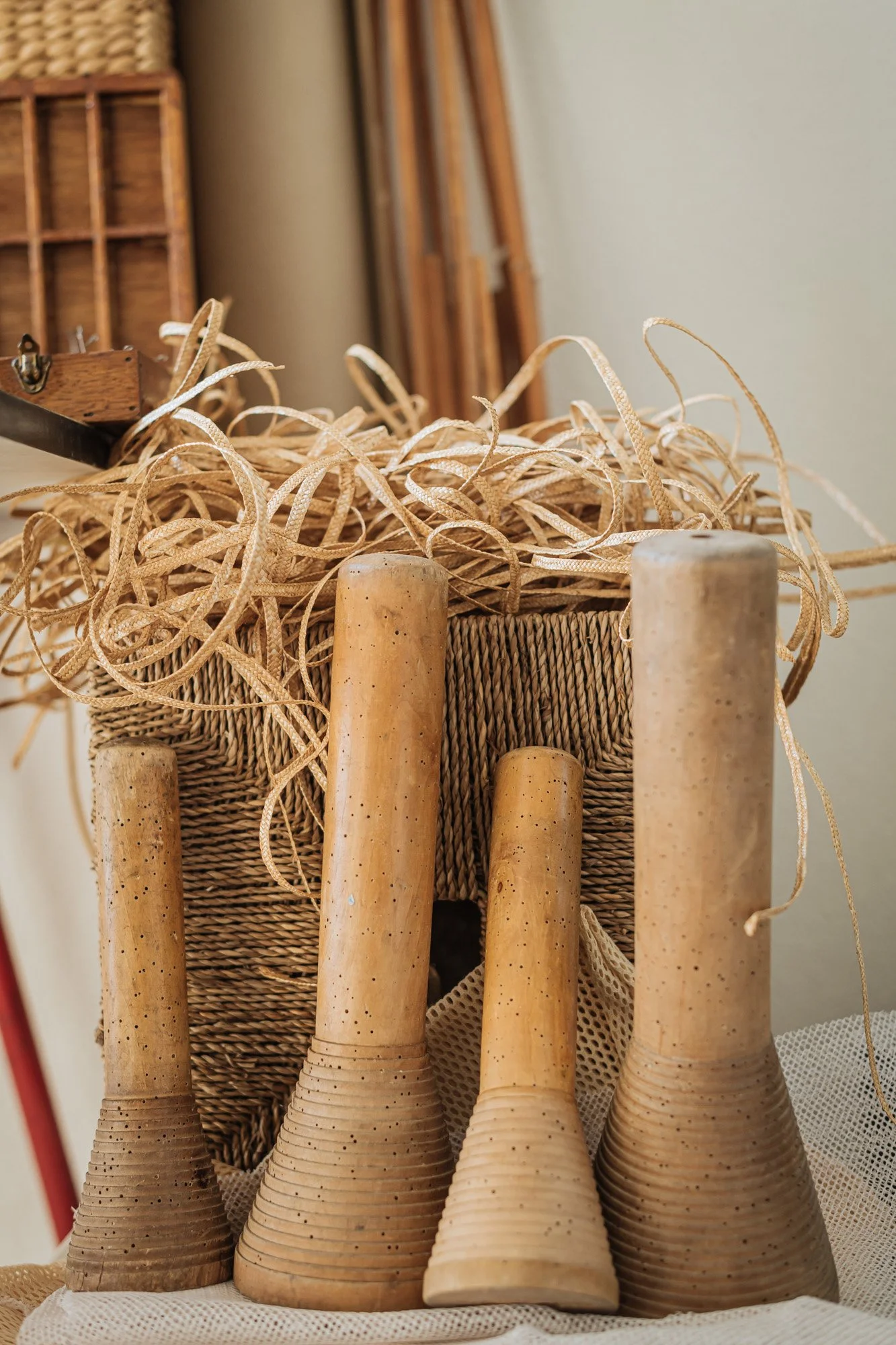 Quatre moulins à vent en bois de différentes tailles, positionnés devant un panier en osier et un tas de ficelle.