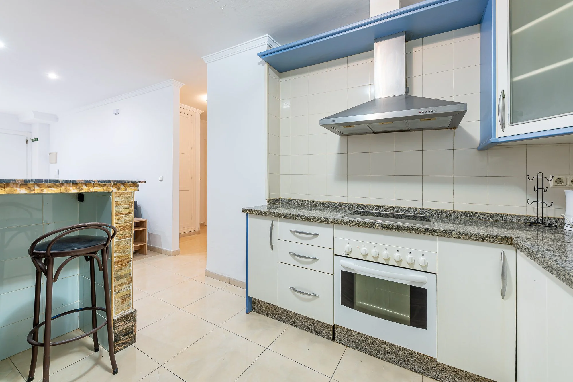 SpainBreaks | Kitchen with white cabinets, granite countertop, induction cooker and oven.