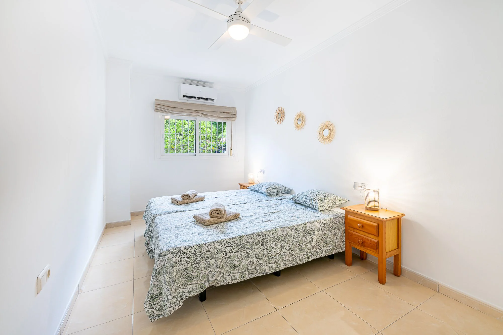 SpainBreaks | Bedroom 1 with two beds, each bed has a  nightstand with a lamp, USB socket, and a ceiling fan with a light.