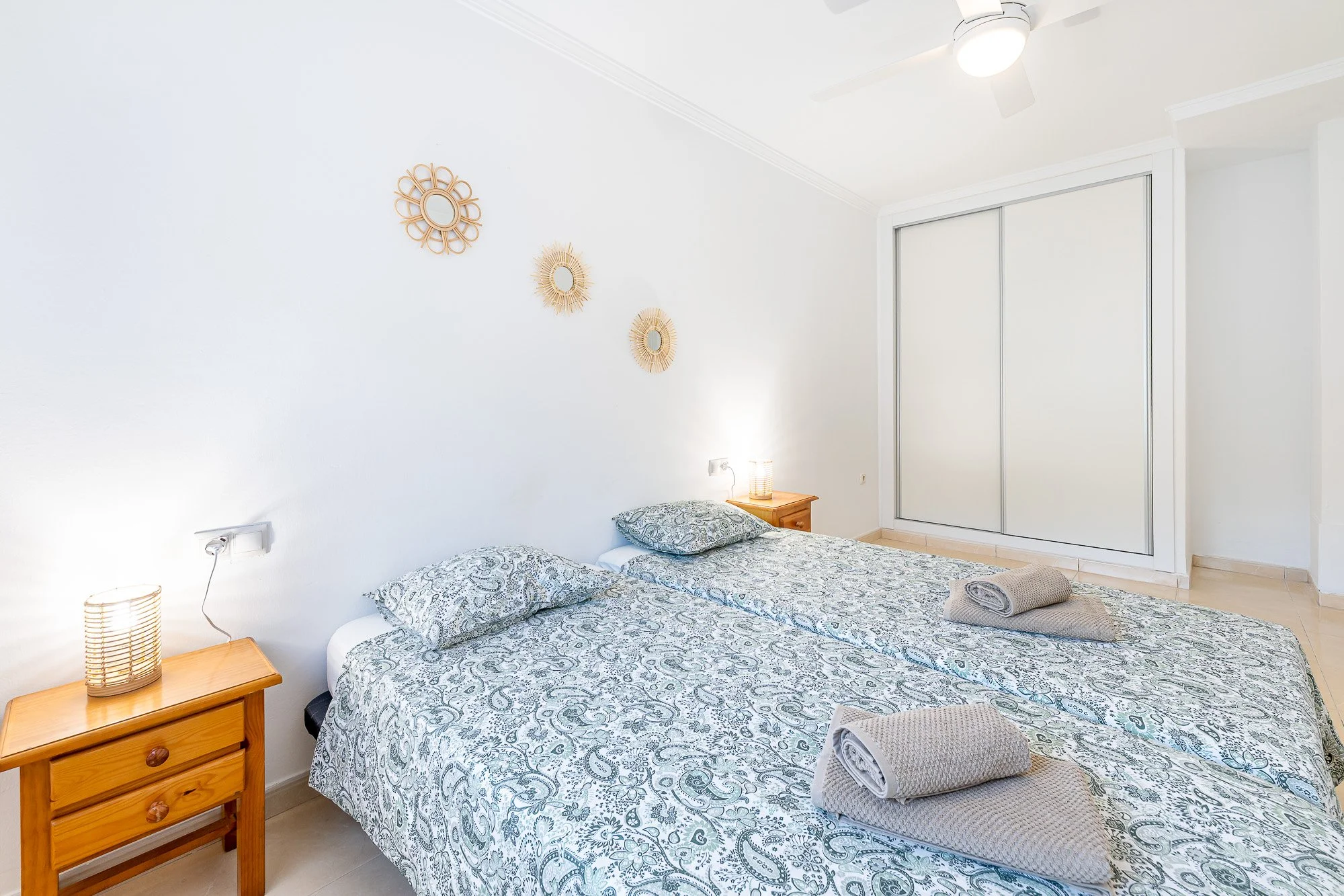 SpainBreaks | Bedroom 1 with double wardrobe, two beds, each bed has a bedside table with a lamp, a USB socket and a ceiling fan with a light.