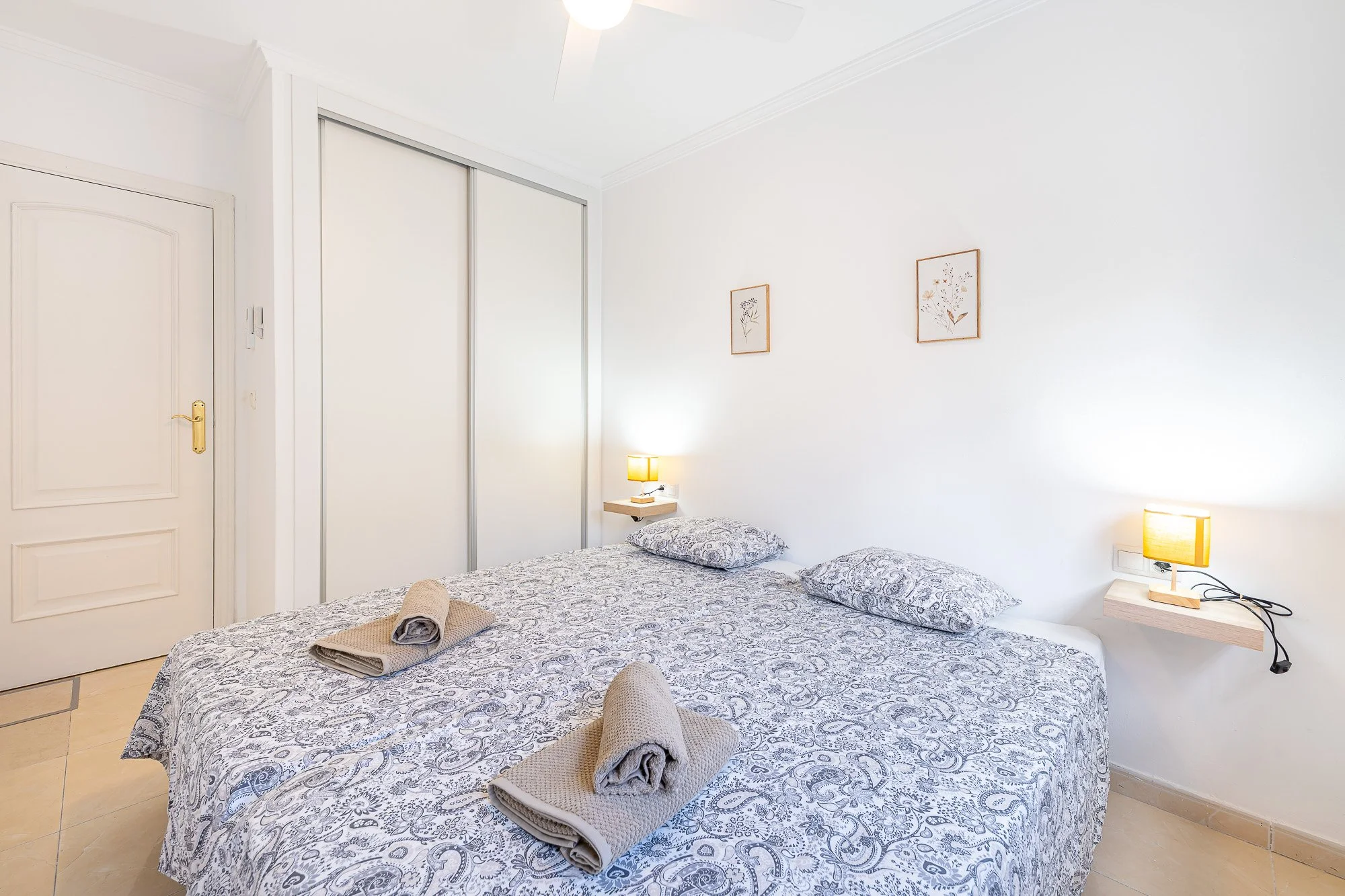 SpainBreaks | Bedroom 2 with double wardrobe, two beds, each bed has a bedside table with a lamp, a USB socket and a ceiling fan with a light.