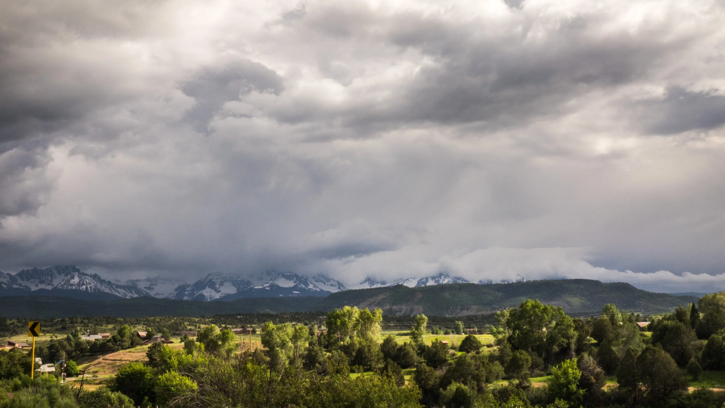 Cloudy sky over a green landscape with mountains in the background