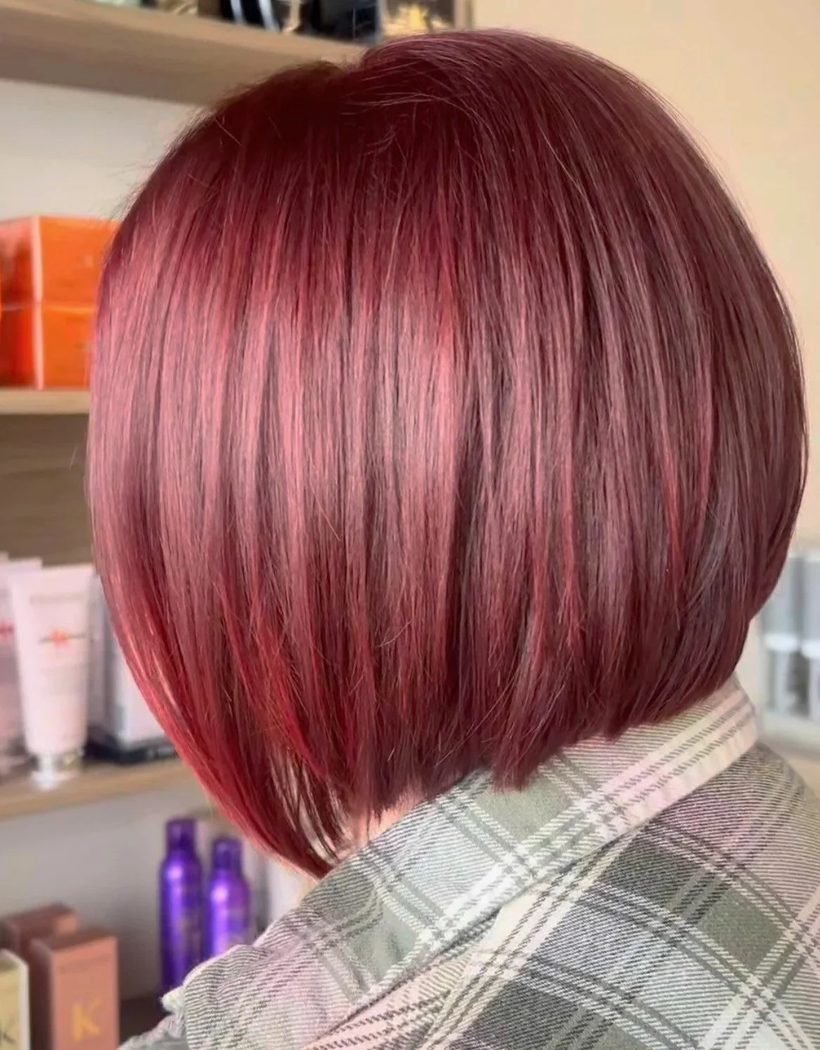 A person's head with a short, straight, layered bob haircut dyed in shades of pink and red.