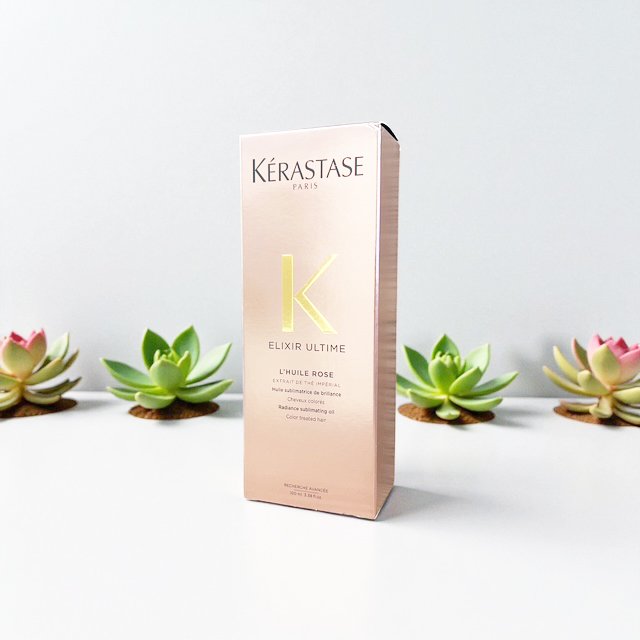 Pink box of Kérastase Paris Elixir Ultime hair oil with green and pink succulents in the background.