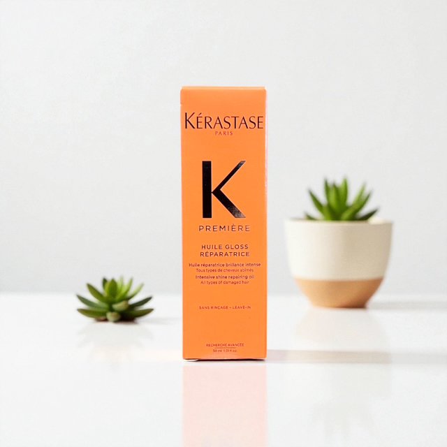 Orangewhite box of Kérastase Paris hair oil product with succulents in background.
