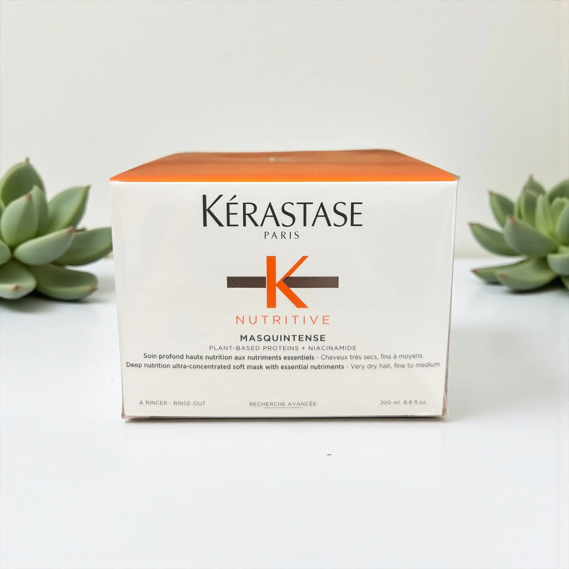 Kérastase Nutritive Masquintense hair mask box with succulents on white background