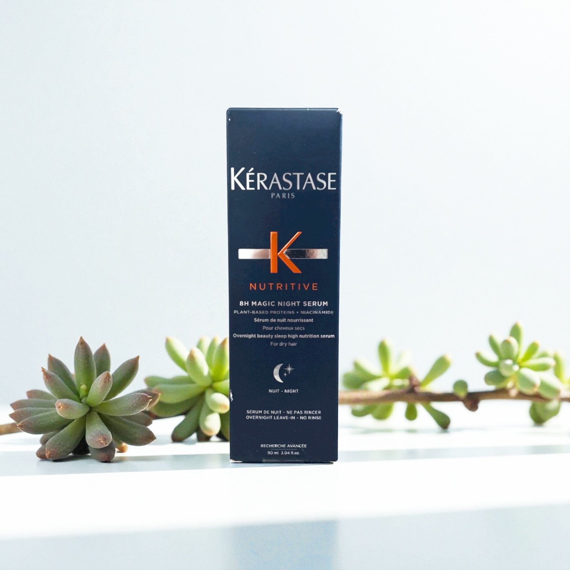 Kérastase Nutritive 8H Magic Night Serum box placed on a white surface with succulents in the background.