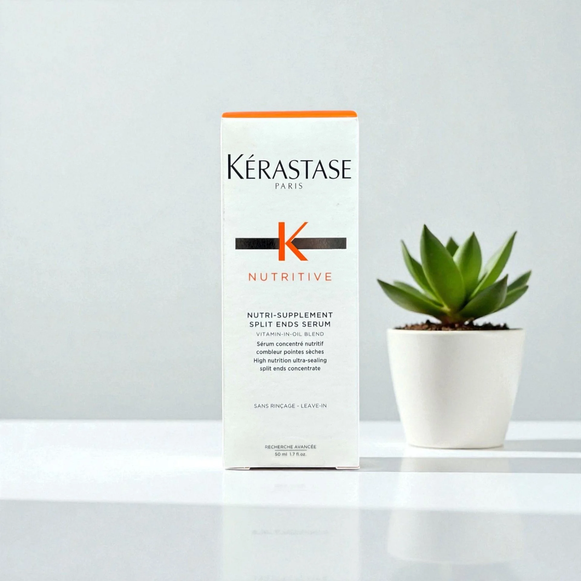 Kérastase Nutritive Nutri-Supplement Split Ends Serum box next to a small potted succulent plant on a white surface with a plain background.