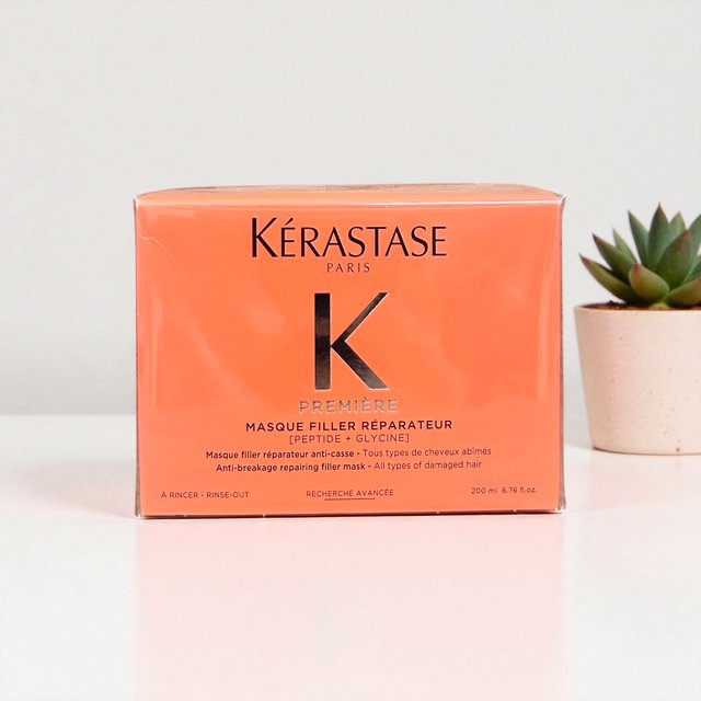 A box of Kérastase Paris hair repair mask with a small potted succulent plant next to it.