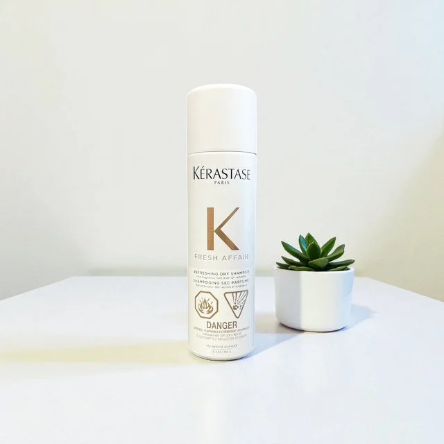 A can of Kérastase Paris Fresh Affair refreshing dry shampoo next to a small potted succulent plant on a white surface against a plain white background.