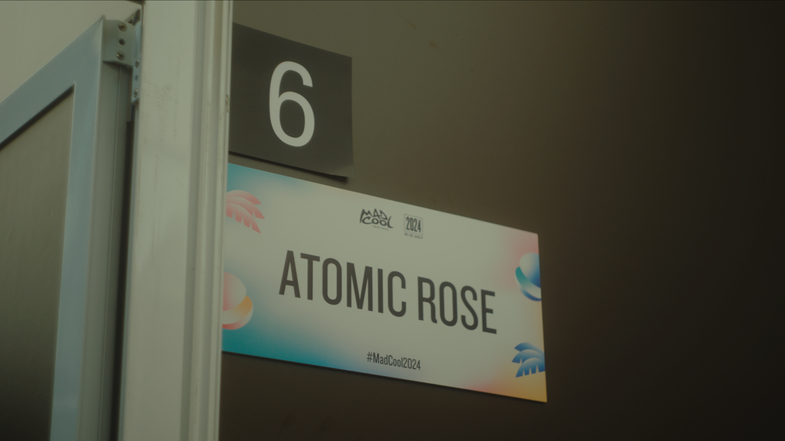 A sign on a door with the words "Atomic Rose" and the hashtag "#MadCool2024". The door is labeled with the number 6.