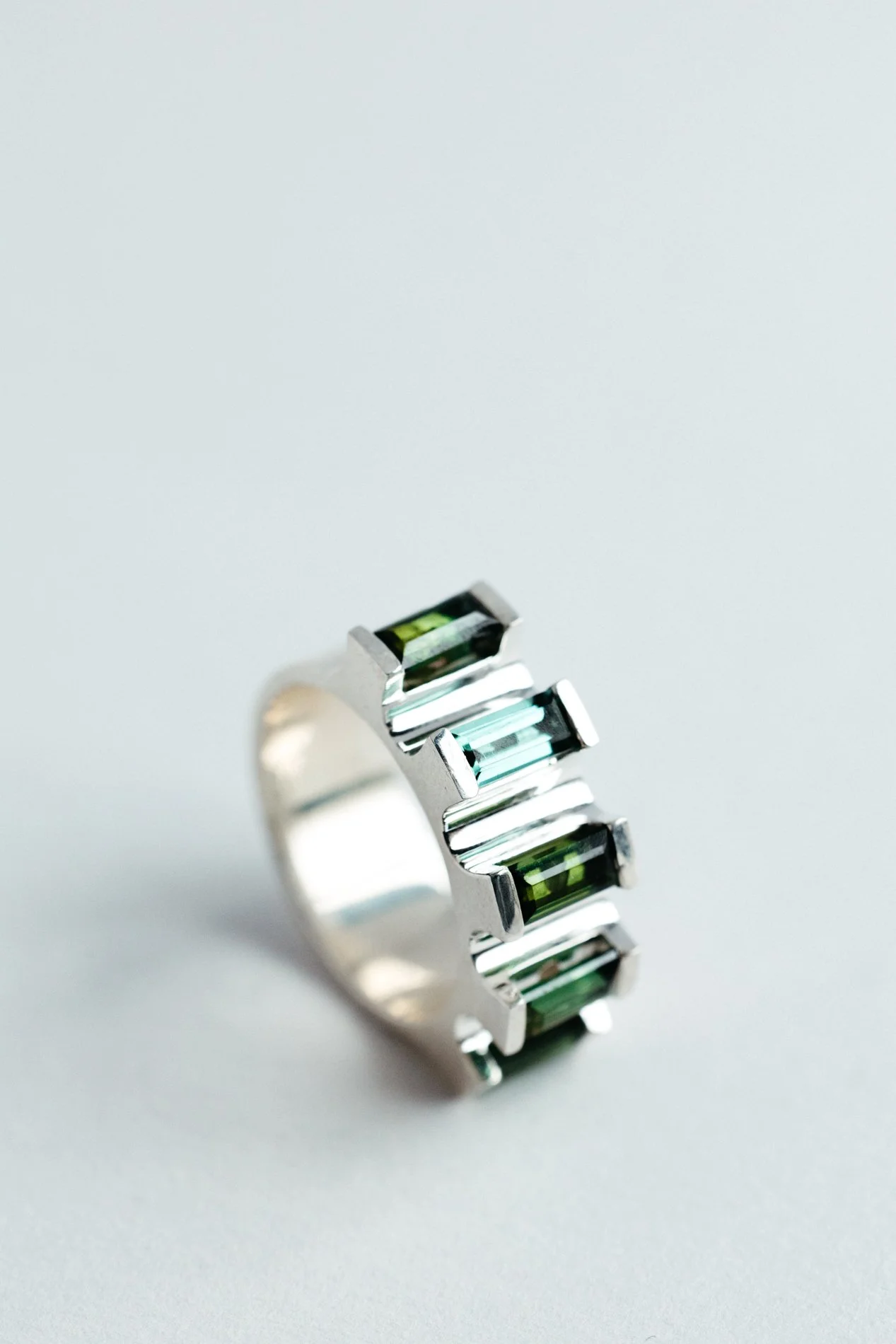 Engrenages ring V4.3 by Sajfrt — silver or gold sprocket-form ring with green or pink tourmalines. Handcrafted in Belgium with precise movement.