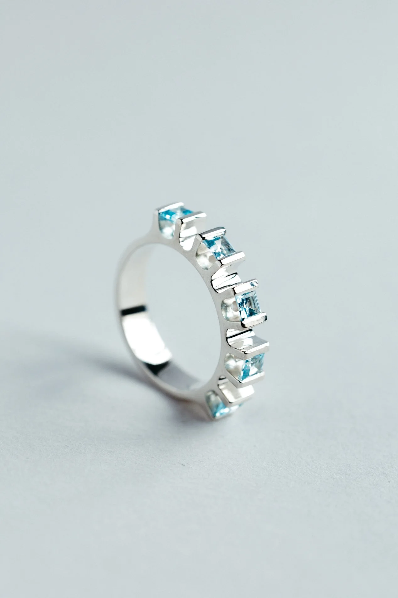 Engrenages ring V4.1 by Sajfrt — sprocket-inspired silver or gold ring with aquamarines or tourmalines. Handcrafted in Belgium with quiet geometry.