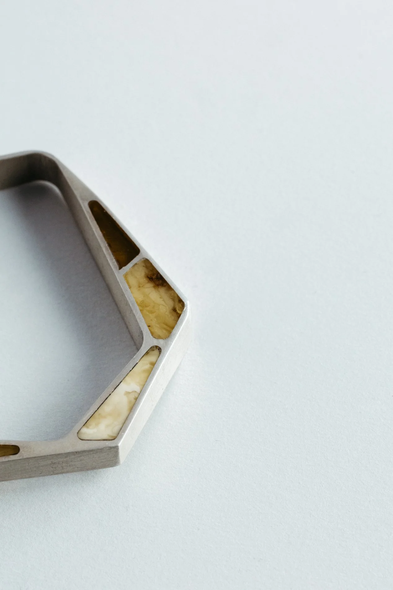 Engrenages bracelet V1.1 by Sajfrt — closed interlocking form in silver or gold with amber stone. Handcrafted in Belgium with architectural intent.