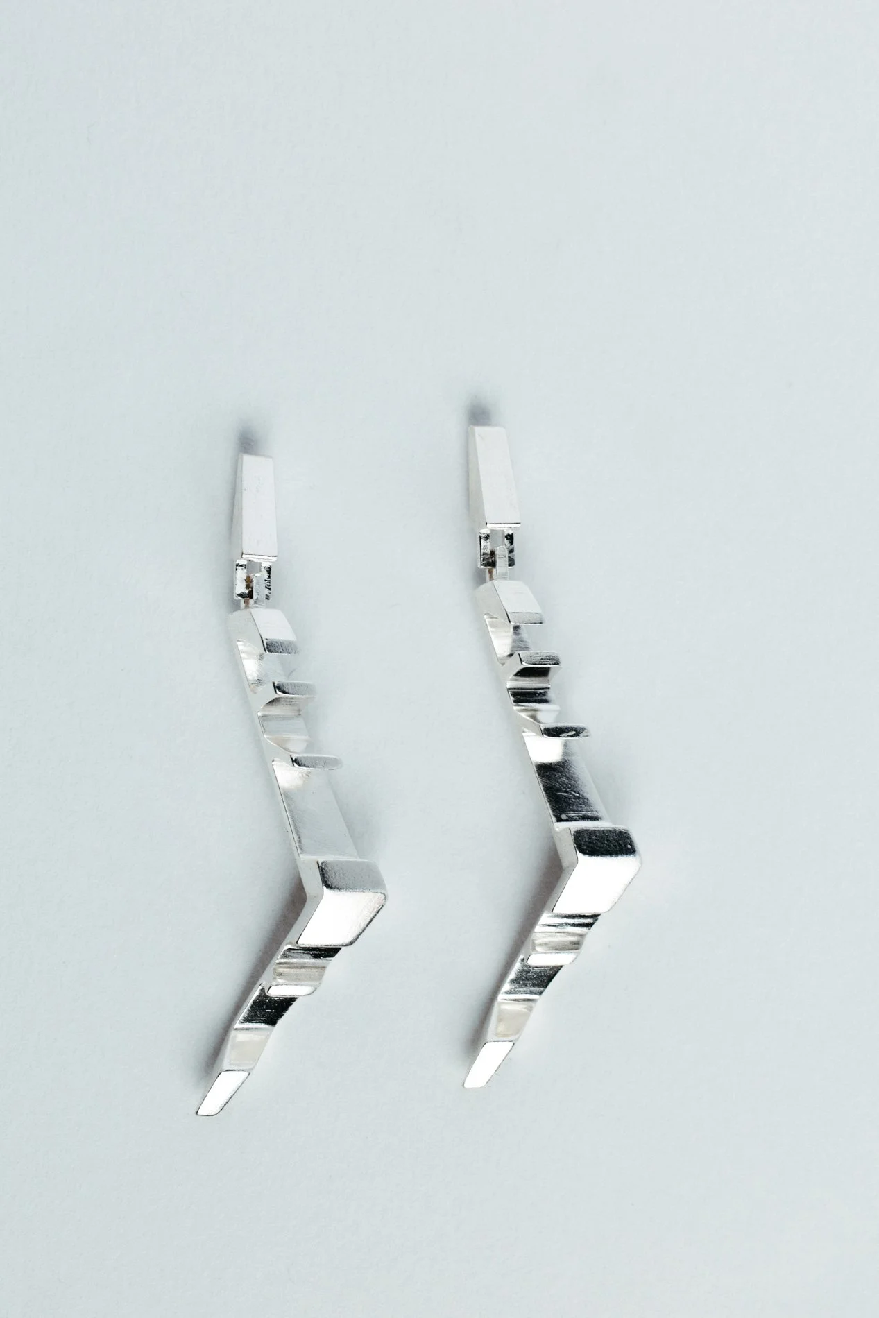 Engrenages earrings V2.2 by Sajfrt — long sprocket-inspired form in silver or gold, handcrafted in Belgium with rotational geometry and presence.