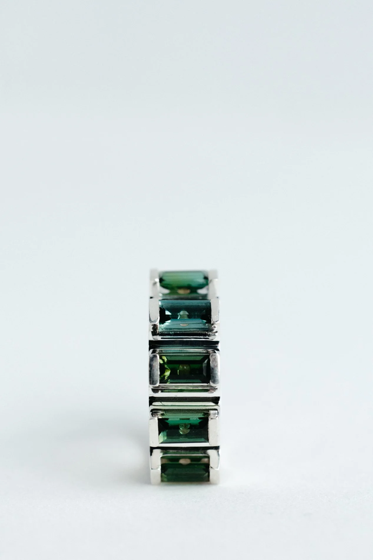 Engrenages ring V4.3 by Sajfrt — silver or gold sprocket-form ring with green or pink tourmalines. Handcrafted in Belgium with precise movement.