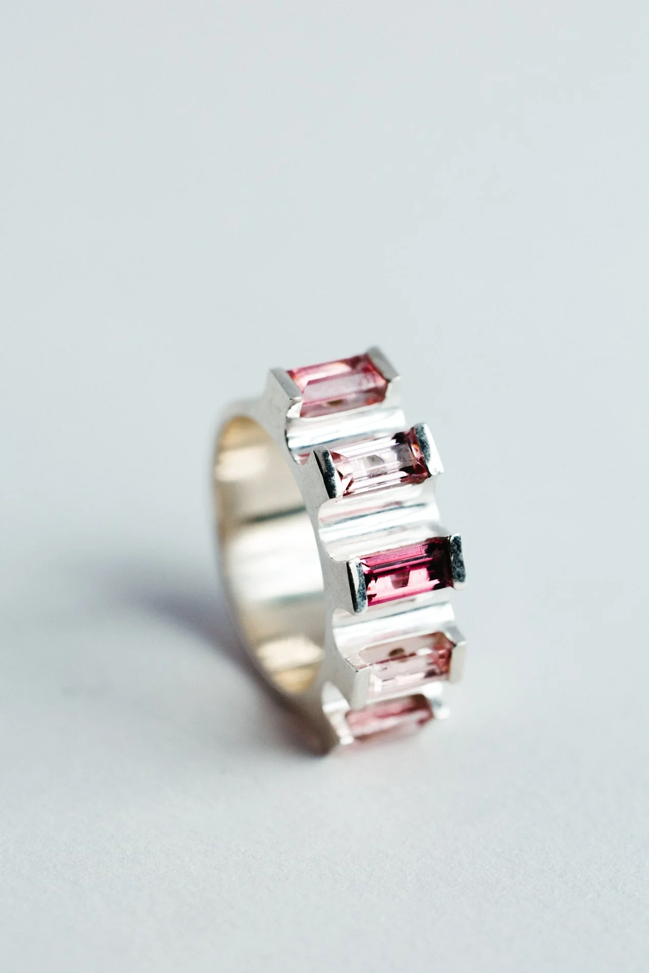 Engrenages ring V4.3 by Sajfrt — silver or gold sprocket-form ring with green or pink tourmalines. Handcrafted in Belgium with precise movement.